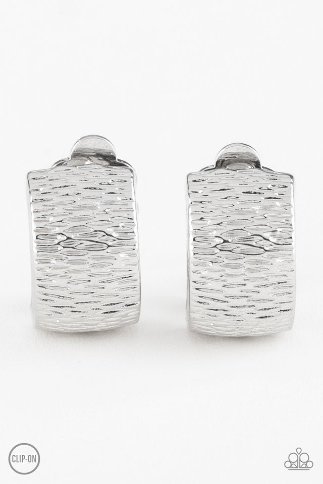 Rippling with tactile textures, a shimmery silver ribbon curls into an edgy frame for a causal look. Earring attaches to a standard clip-on fitting. Sold as one pair of clip-on earrings.