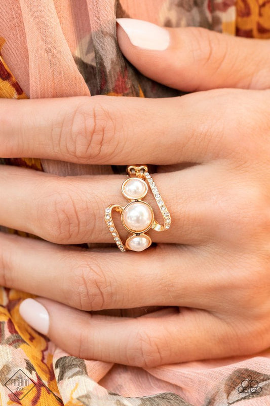 A golden ribbon of white rhinestones whirls around and behind a single band of three bubbly white pearls, coalescing into a timeless twinkle atop the finger. Features a dainty stretchy band for a flexible fit.  Fiercely 5th Avenue August 2021
