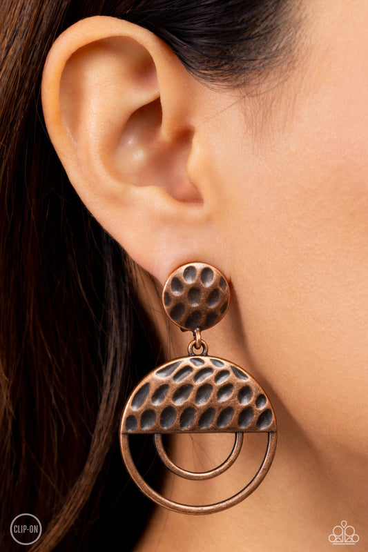 Paparazzi Accessories - Southern Souvenir - Copper Clip-On Earrings a hammered copper disc gives way to a circular copper frame that is capped in a hammered half moon copper accent, resulting in a rustic lure. Earring attaches to a standard clip-on fitting.  Sold as one pair of clip-on earrings.