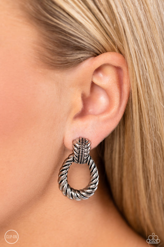 Paparazzi Accessories - Roping Rodeo - Silver Clip-On Earrings featuring twisted ropelike texture, an antiqued loop attaches to a studded silver fitting for a rustic flair. Earring attaches to a standard clip-on fitting.  Sold as one pair of clip-on earrings.