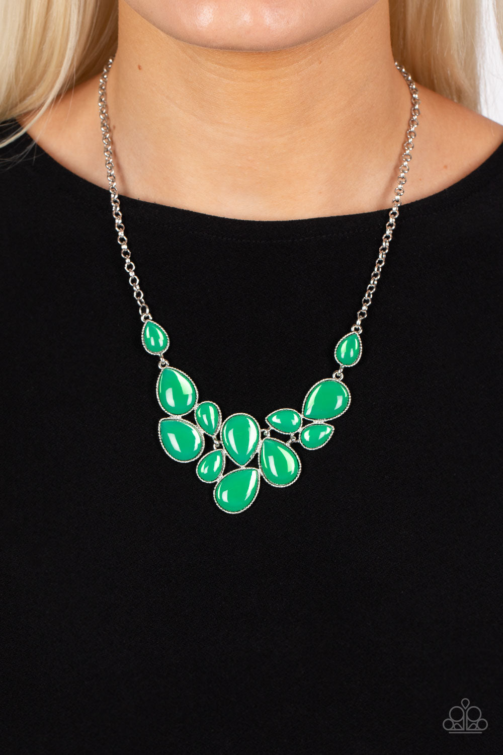 Paparazzi Accessories - Keeps GLOWING and GLOWING - Green Necklaces a cascade of glassy green teardrops are encased in studded silver frames, ultimately clustering below the collar to create an enchanting pop of color. Features an adjustable clasp closure. Sold as one individual necklace. Includes one pair of matching earrings.