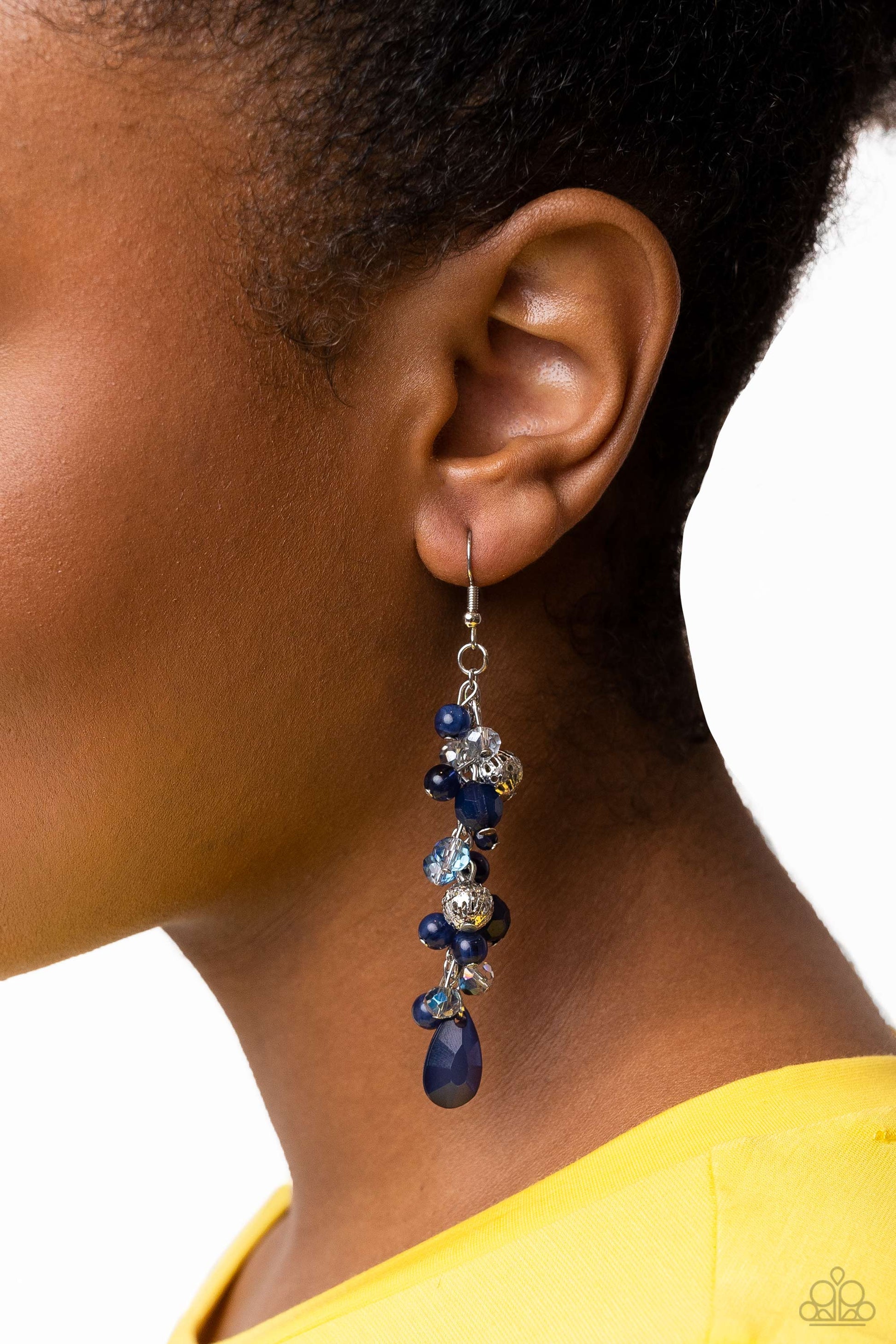 boisterous collection of blue teardrop and round beads, textured silver accents, and faceted blue crystal-like beads trickle from a double strand of silver chain, resulting in flirtatious layers down the neckline. Features an adjustable clasp closure. A dainty collection of blue teardrop and round beads, textured silver accents, and faceted blue crystal-like beads trickle from a single strand of silver chain, resulting in a cheekily clustered chandelier. Earring attaches to a standard fishhook fitting.