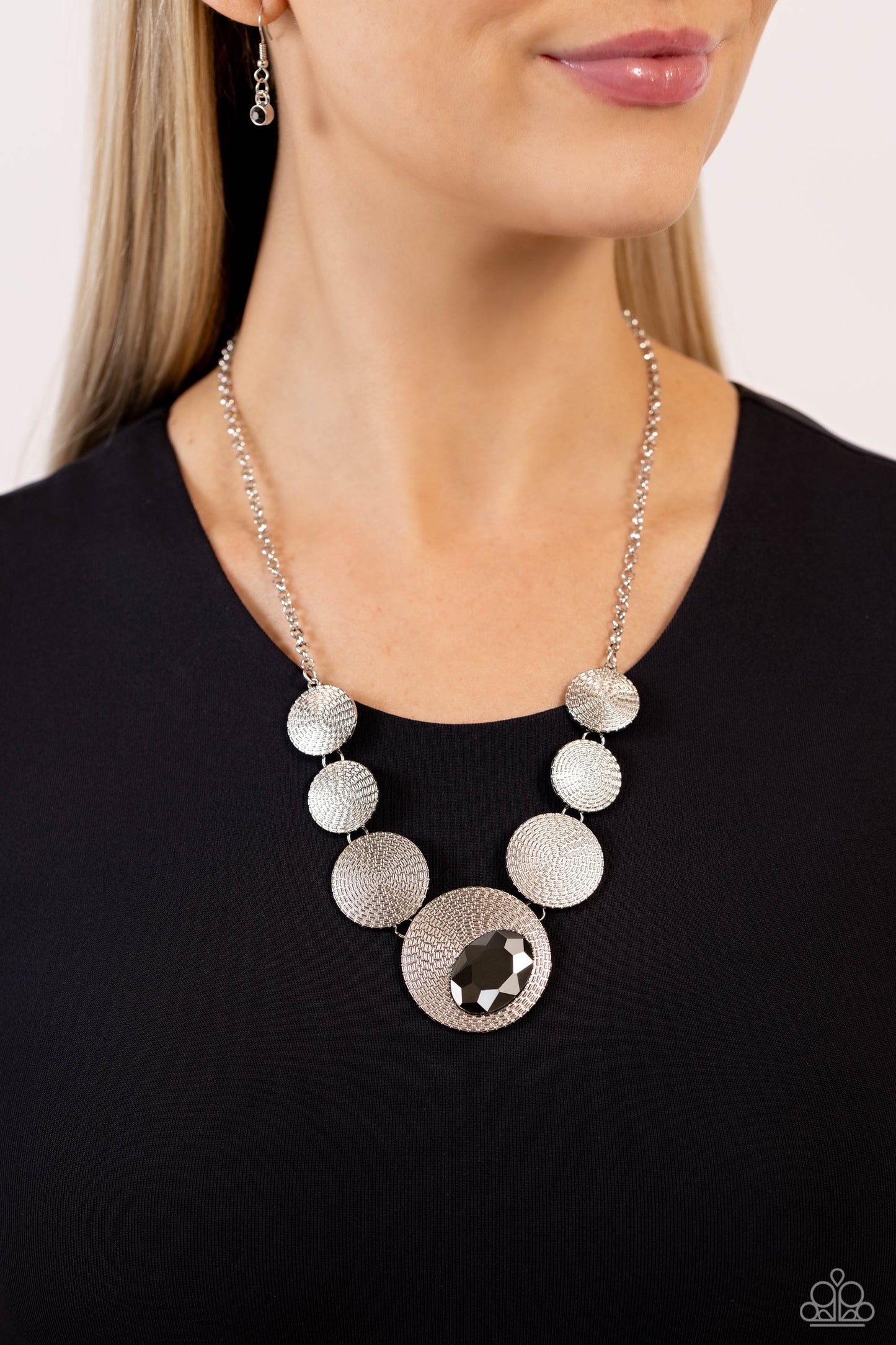 Paparazzi Accessories - EDGY or Not - Silver Necklaces embossed in an elongated dotted motif, a rustic collection of silver discs in varying sizes ruggedly links below the collar for an artisan inspired fashion. A faceted, oval, hematite gem sits at an angle on the biggest disc for a dauntless pop of color against the neckline. Features an adjustable clasp closure. Featured inside The Preview at Made for More! Sold as one individual necklace. Includes one pair of matching earrings.