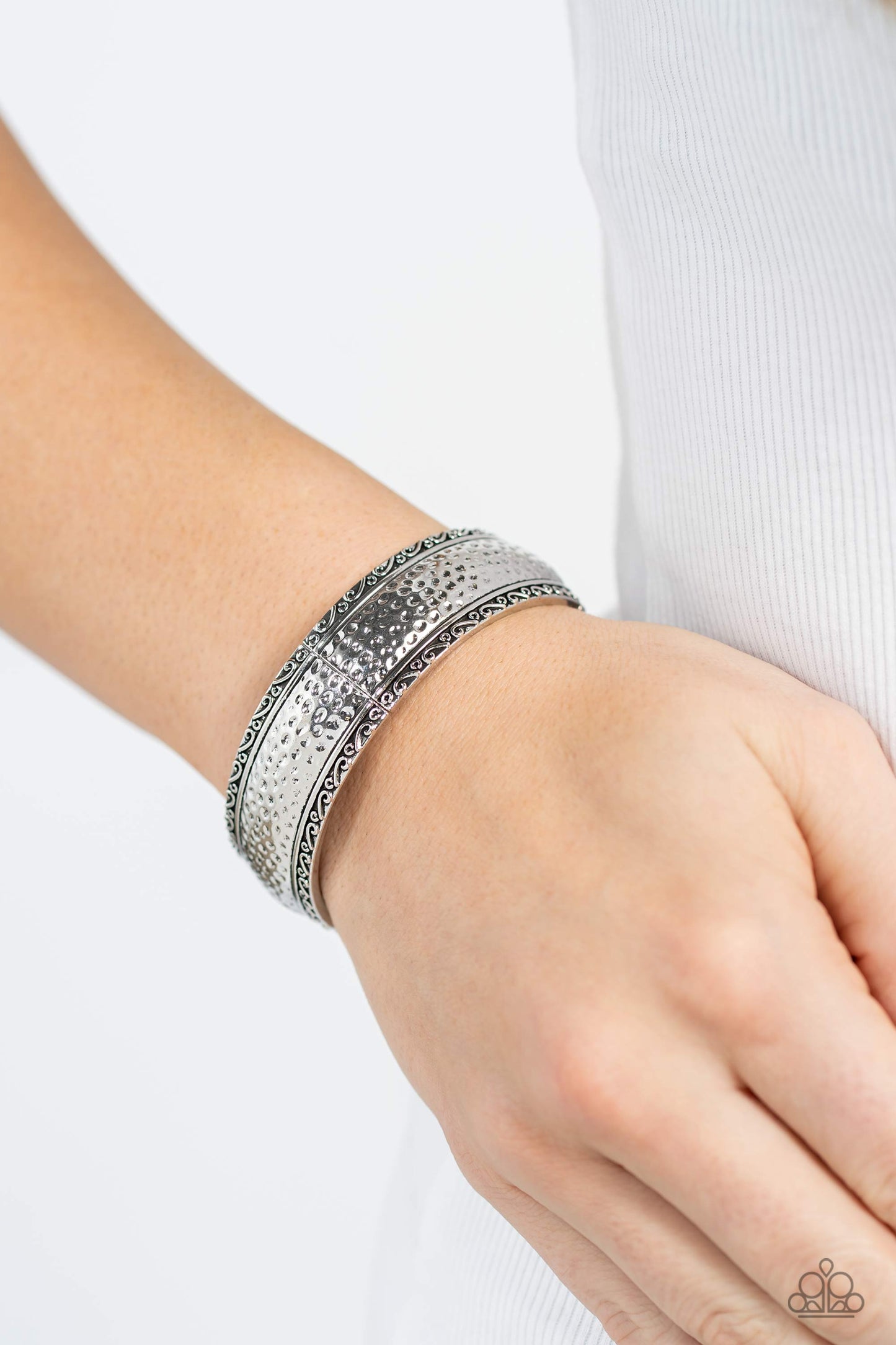 Paparazzi Accessories - Textile Tenor - Silver Bracelet curved frames of high-sheen silver curve around the wrist on elastic stretchy bands. Studs and ribbons of silver curl into a dainty filigree above and below its hammered center for a soft and dauntless combo. Sold as one individual bracelet.