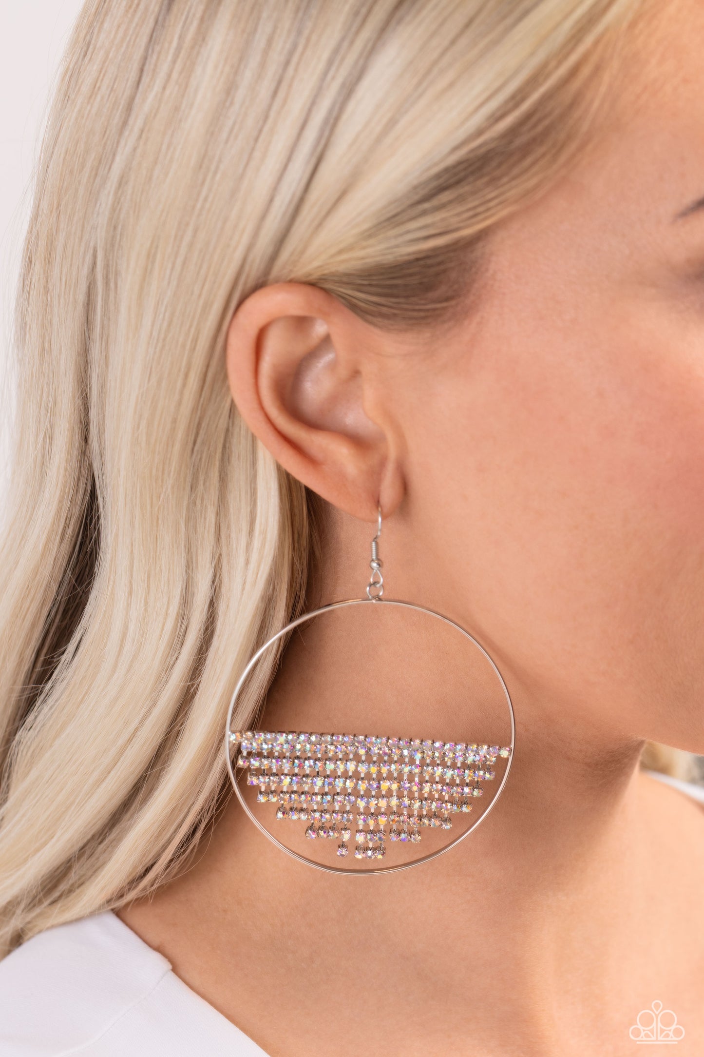 Paparazzi Accessories - Fierce Fringe - Multi Earrings a curtain of iridescent rhinestones is stretched between the edges of a skinny, oversized silver hoop, creating a shimmering display. The rhinestones taper towards the center as they sway and cascade, adding sparkly movement for a fierce industrial finish. Earring attaches to a standard fishhook fitting. Due to its prismatic palette, color may vary. Sold as one pair of earrings.