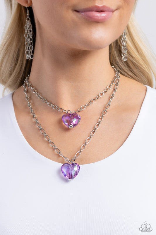 Paparazzi Accessories - Layered Love - Purple Heart Necklaces featuring a subtle iridescent shimmer, two glassy purple gem hearts are delicately suspended above one another on a paperclip and silver oval link chain for a whimsical double-stacked display. Features an adjustable clasp closure.  Sold as one individual necklace. Includes one pair of matching earrings.