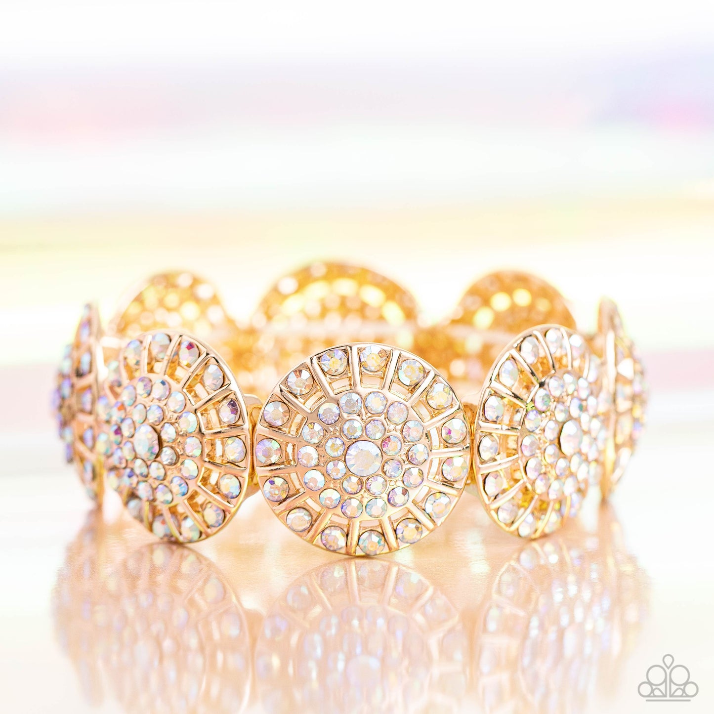 Paparazzi Accessories - Executive Elegance - Multi Bracelets featuring a wheel motif, concaved gold discs embossed in an explosion of iridescent rhinestones slide along a stretchy band around the wrist for a hint of dazzling refinement. Due to its prismatic palette, color may vary. Sold as one individual bracelet.