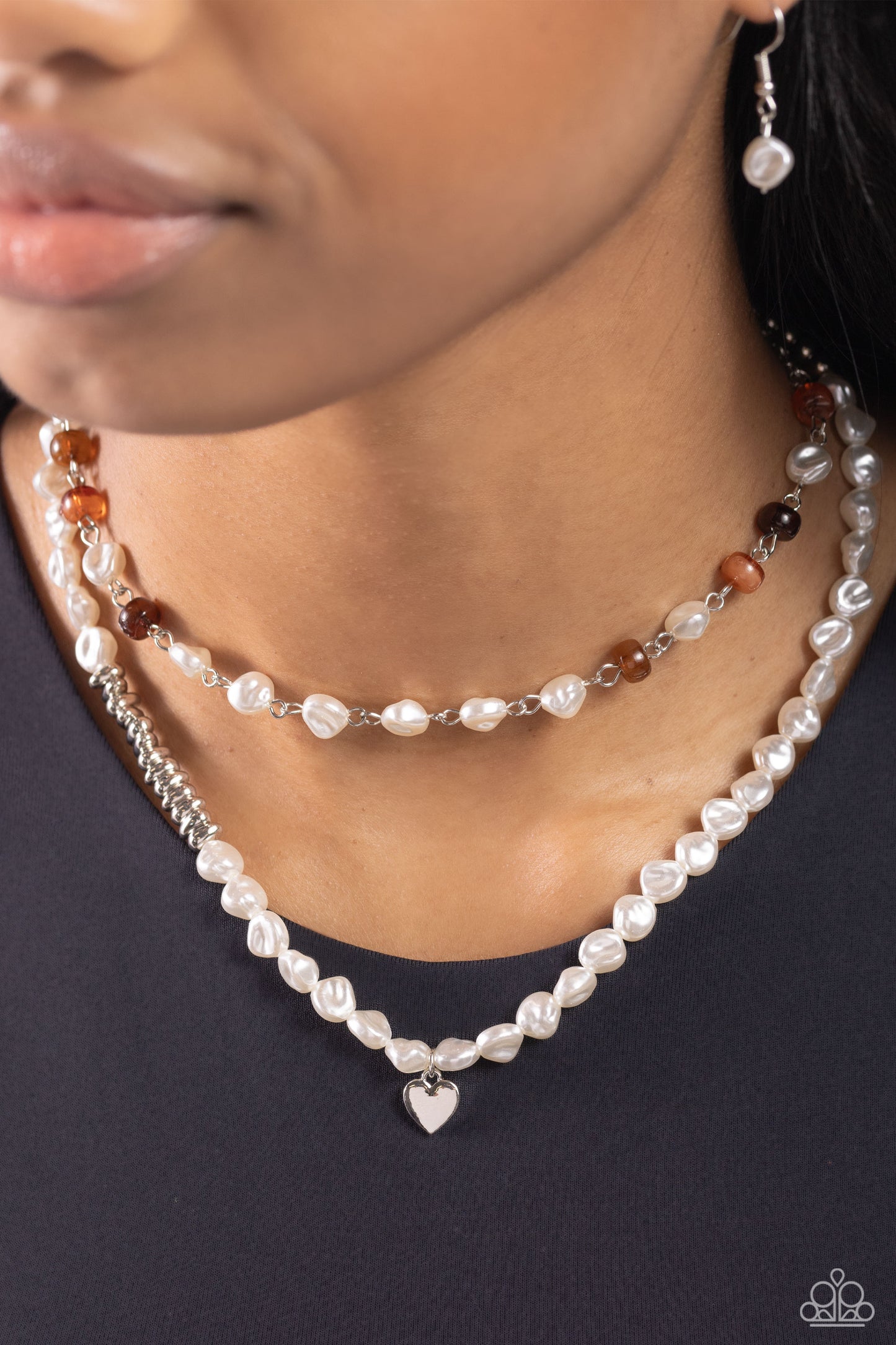Paparazzi Accessories - Pearl Pact - Brown Necklaces infused with various brown cat's eye discs, a baroque pearl beaded strand gives way to an elongated baroque pearl and silver beaded strand featuring a dainty silver heart pendant for a whimsically layered look. Features an adjustable clasp closure. Sold as one individual necklace. Includes one pair of matching earrings.