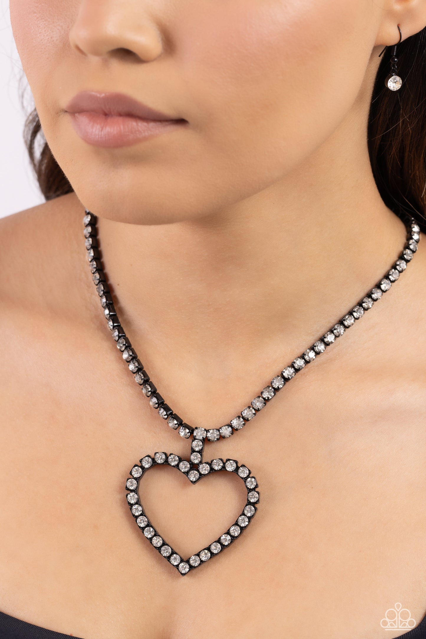 Paparazzi Accessories - Flirting Fancy - Black Necklaces featuring pronged, square black fittings, glassy white rhinestones encircle the neckline and lead the eye down to an airy heart silhouette, resulting in a flirtatious sparkle. Features an adjustable clasp closure. Sold as one individual necklace. Includes one pair of matching earrings.