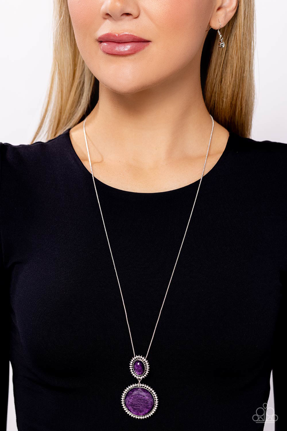 Paparazzi Accessories - Castle Cadenza - Purple Neckencasfeaturing a scratched motif, a large purple gem is encased in a border of rhinestone-dusted silver, as it's suspended from a smaller version of the same design but in an oval shape. The stacked pendant then slides along an elongated silver snake chain for a regal finish. Features an adjustable clasp closure. Sold as one individual necklace. Includes one pair of matching earrings.