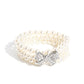 Paparazzi Accessories - How Do You Do? - White Pearl Bracelet strung along elastic stretchy bands, three strands of high-sheen classic white pearls wrap around the wrist. Featured atop the pearly collection, a loopy silver bow, filled with glistening white rhinestones is attached to the center of the wrist for a dramatically dazzling finish.  Sold as one individual bracelet.