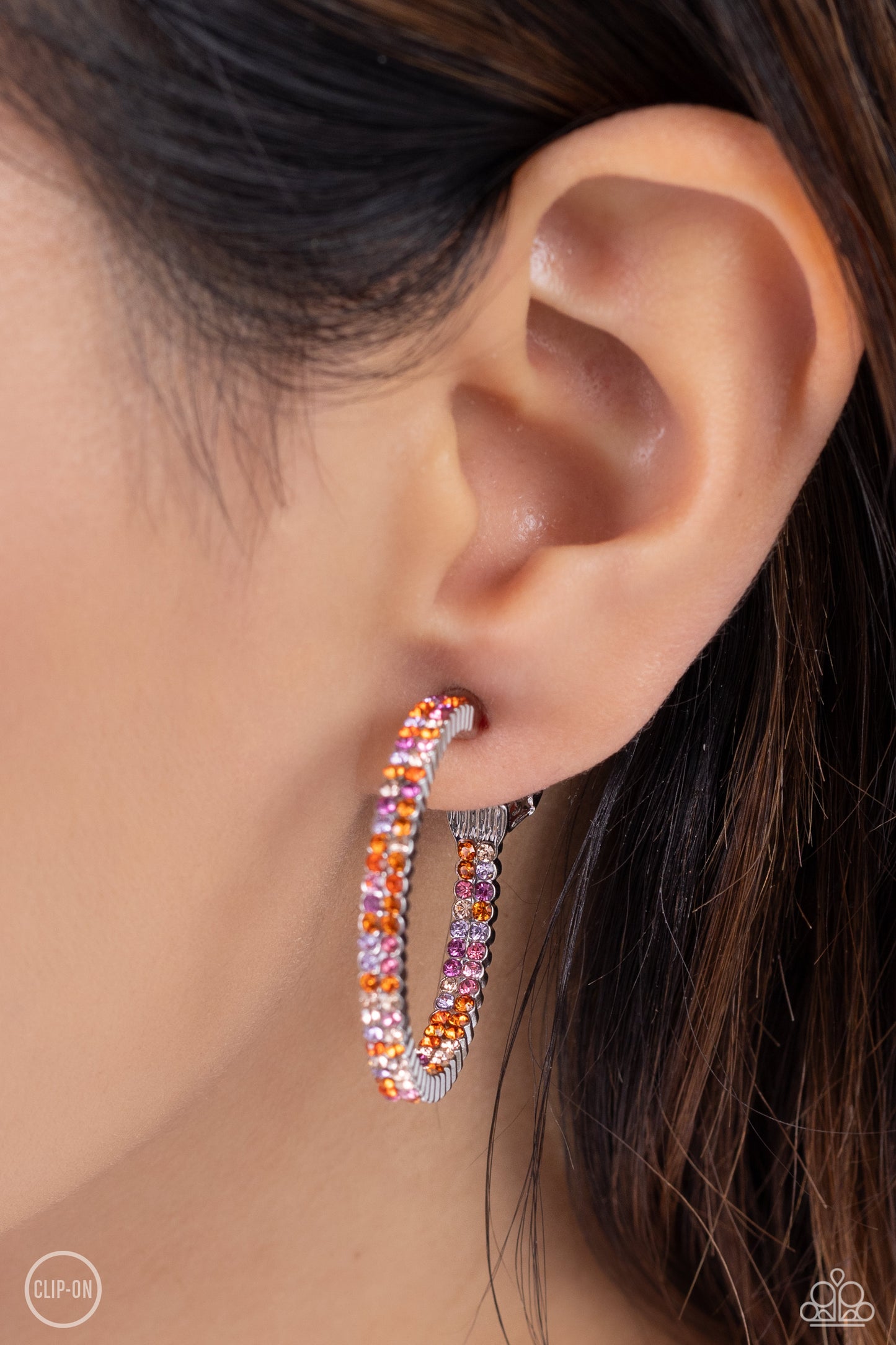 Paparazzi Accessories - Outstanding Ombre' - Orange Clip-On Earrings the front half and lower inner curve of a textured silver hoop are encrusted in dazzling ombré shades of orange, pink, and purple for a flawless look. Earring attaches to a standard clip-on fitting. Hoop measures approximately 1" in diameter. Sold as one pair of clip-on earrings.