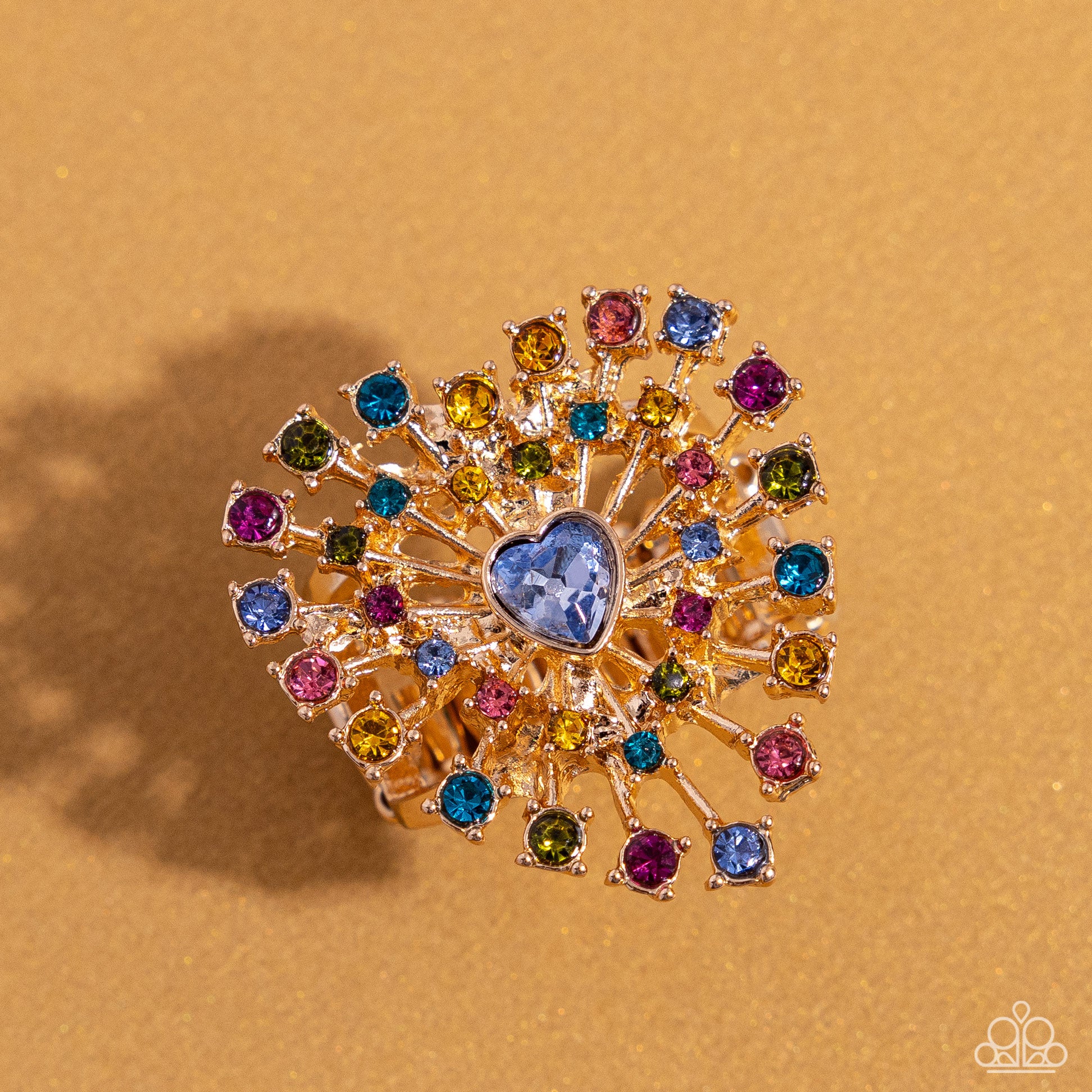 Paparazzi Accessories - Bewitching Beau - January 2024 Life of the Party - Multi Ring set in pronged gold square fittings, multicolored round rhinestones circle a light sapphire heart gem in a sunburst pattern for a bewitching display. Features a stretchy band for a flexible fit.  Sold as one individual ring.