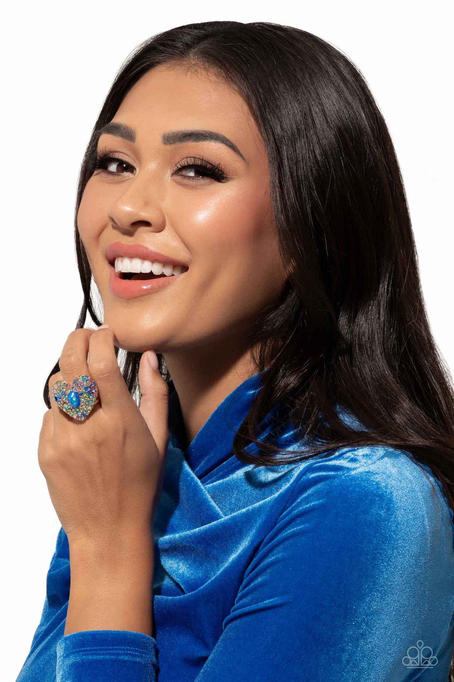Encrusted in brilliant multicolored and iridescent rhinestones, a glittery gold heart frame adorns the center of an airy gold band for a flirtatious finish. Featuring iridescent flecks, an opalescent blue oval bead is pressed in the center of the heart frame for additional eye-catching shimmer. Features a stretchy band for a flexible fit. Due to its prismatic palette, color may vary. Sold as one individual ring.