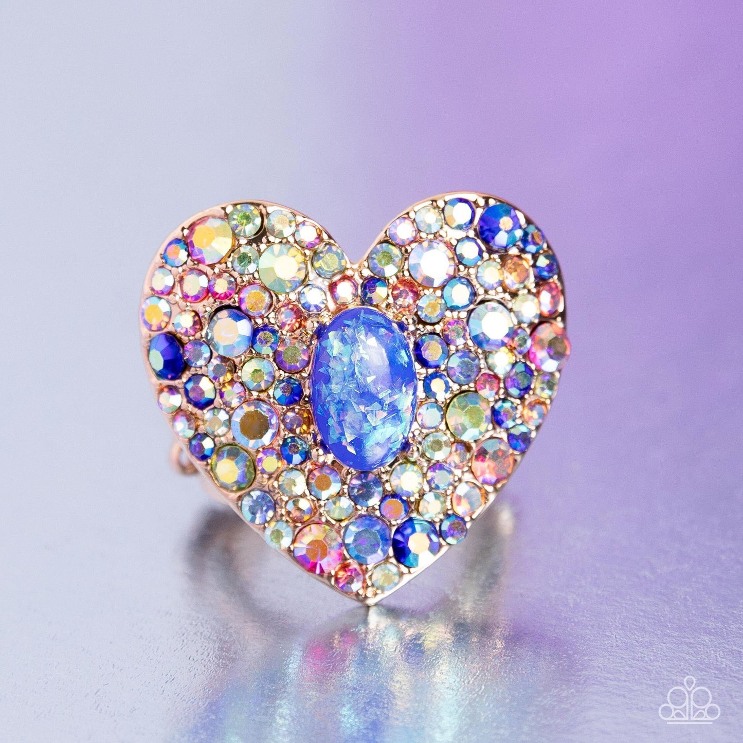 Encrusted in brilliant multicolored and iridescent rhinestones, a glittery gold heart frame adorns the center of an airy gold band for a flirtatious finish. Featuring iridescent flecks, an opalescent blue oval bead is pressed in the center of the heart frame for additional eye-catching shimmer. Features a stretchy band for a flexible fit. Due to its prismatic palette, color may vary. Sold as one individual ring.