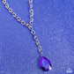 Paparazzi Accessories - Benevolent Bling - Purple Necklaces set in an elevated silver-pronged frame, a faceted purple UV teardrop gem cascades from an oblong, abstract silver ring chain that extends past the collar for a blinding statement. Features an adjustable clasp closure.  Sold as one individual necklace. Includes one pair of matching earrings.