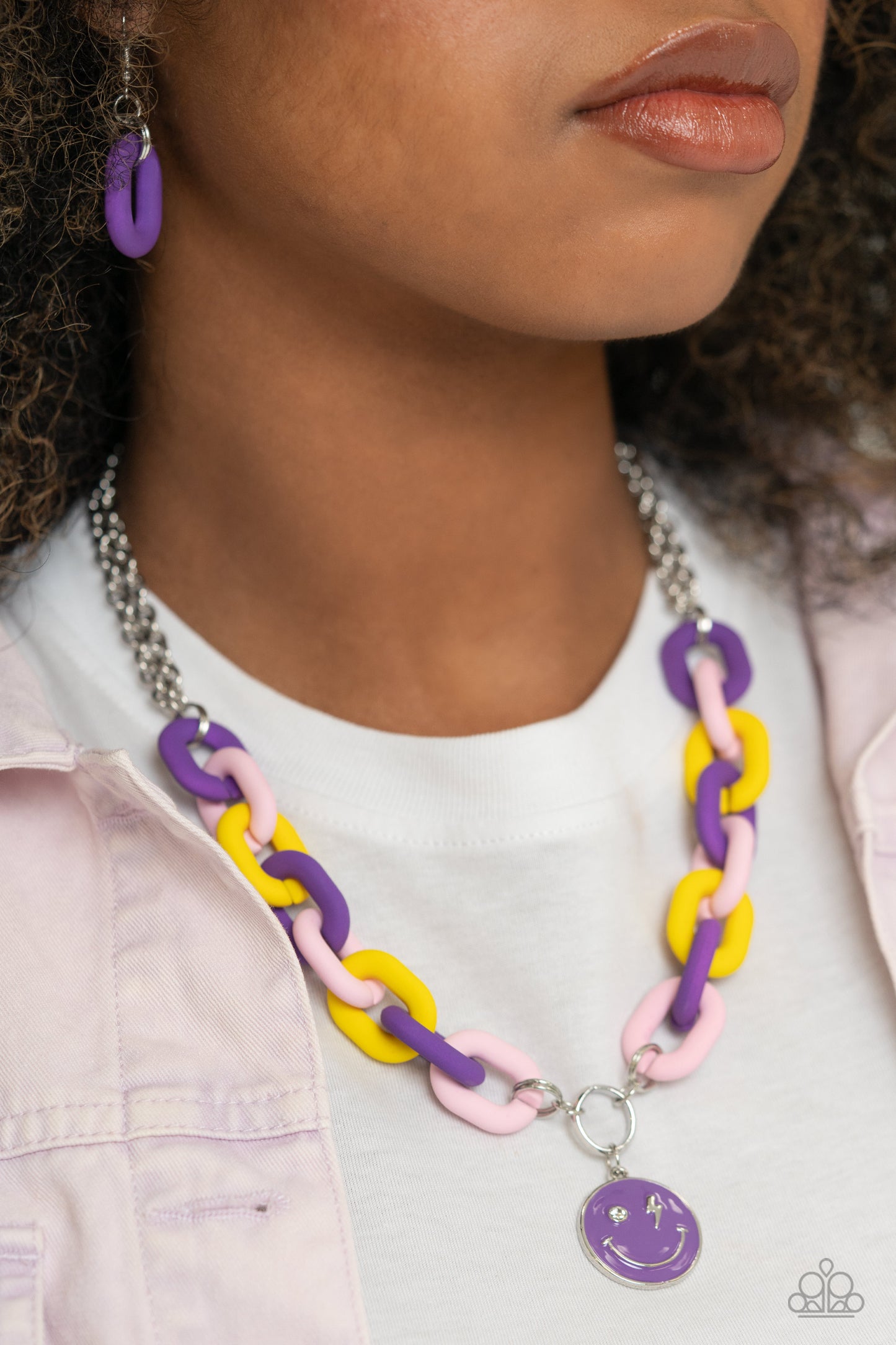 Paparazzi Accessories - Speed Smile - Purple Jewelry Sets two strands of silver chain give way to a strand of oversized purple, baby pink, and yellow acrylic links for a colorful statement. A purple-painted smiley face pendant, with a lightning bolt for one eye, cascades from the colorful links for an exaggerated touch of personality. Features an adjustable clasp closure.