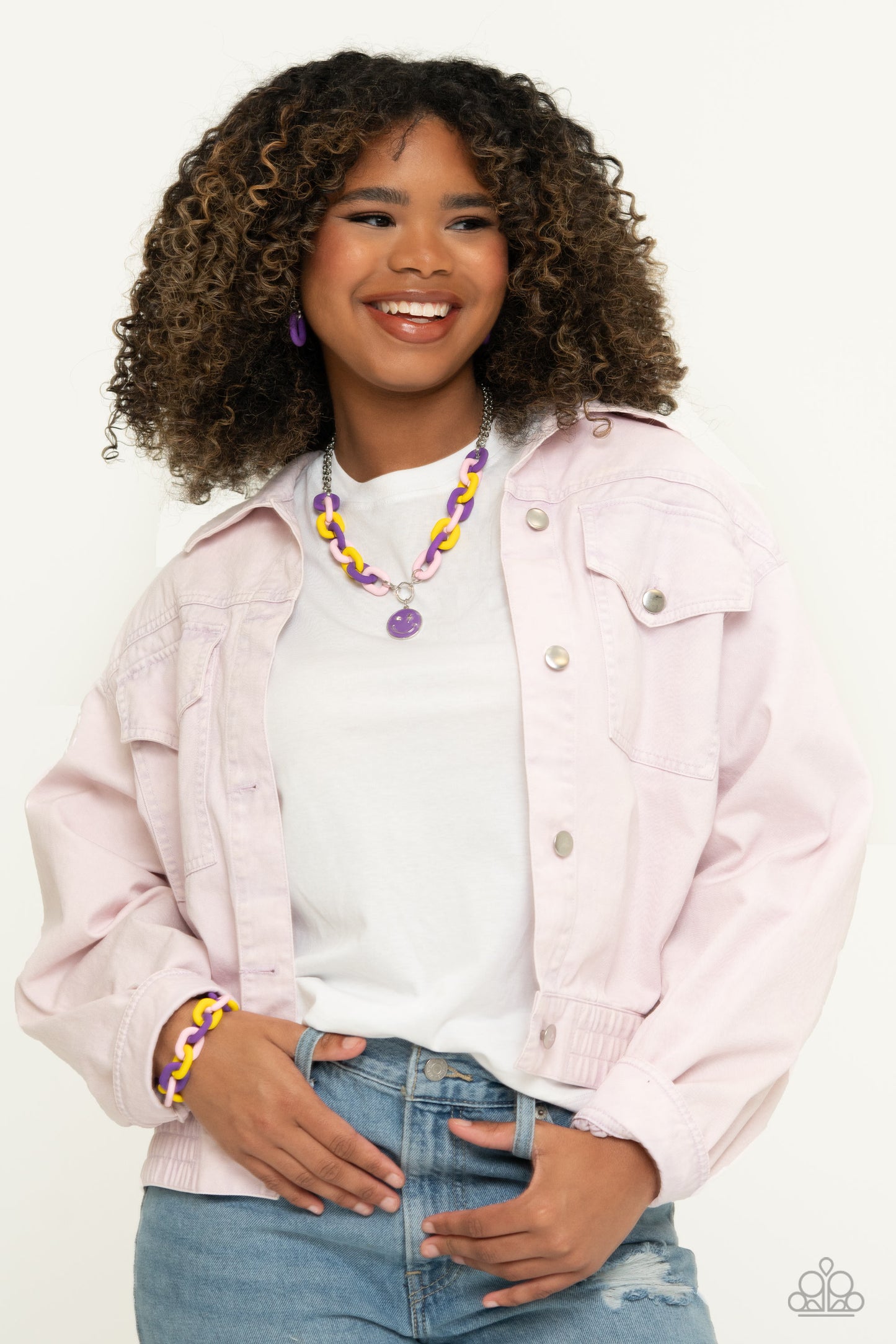 Paparazzi Accessories - Speed Smile - Purple Jewelry Sets two strands of silver chain give way to a strand of oversized purple, baby pink, and yellow acrylic links for a colorful statement. A purple-painted smiley face pendant, with a lightning bolt for one eye, cascades from the colorful links for an exaggerated touch of personality. Features an adjustable clasp closure.