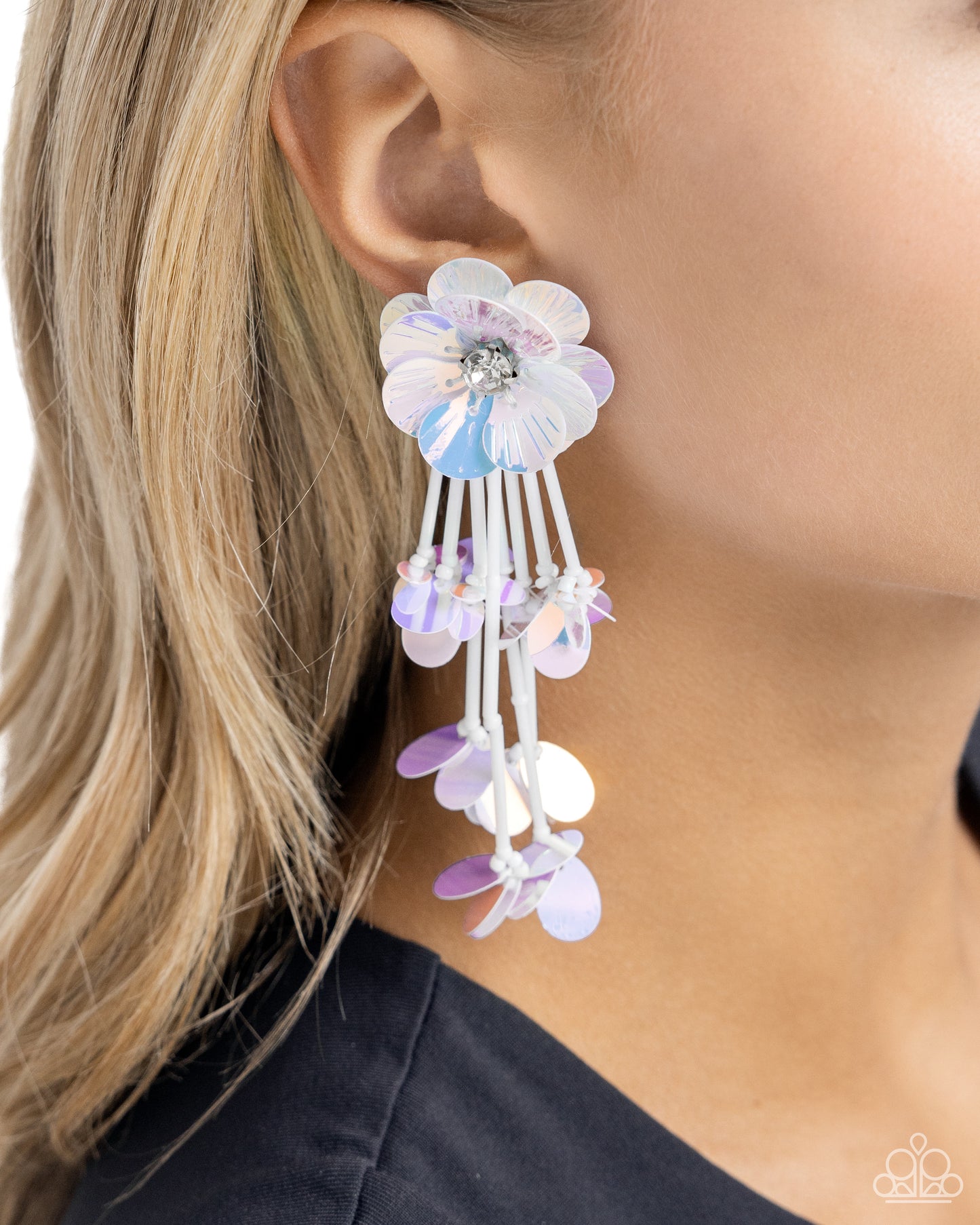 Blooming from a faceted white gem center, textured white iridescent sequin petals give way to a collection of white cylindrical beaded strands that elongate the neck. Sporadically bursting amongst the strands, a collection of simple white iridescent sequins flicker and flash for additional eye-catching interest. Earring attaches to a standard post fitting. Due to its prismatic palette, color may vary. Sold as one pair of post earrings.