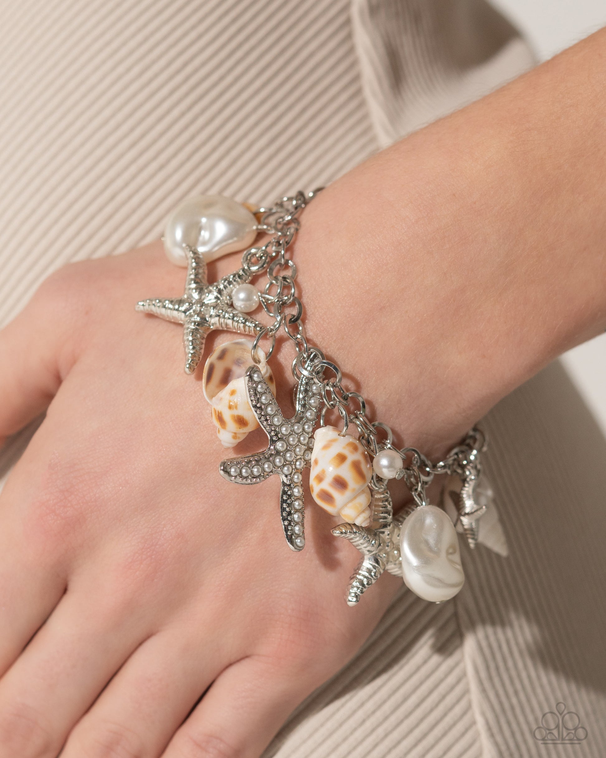 Paparazzi Accessories - Seashell Shanty & Seashell Song - White Jewelry Sets an eclectic display of shimmery silver texture and beach-inspired accents gathers along layered, thick, silver links, creating a boisterous display along the neckline. The hodgepodge of texture and sheen includes textured silver starfish, baroque white pearls, white seashells, dainty white pearls, a dainty white pearl-encrusted silver starfish, and hammered silver rings.