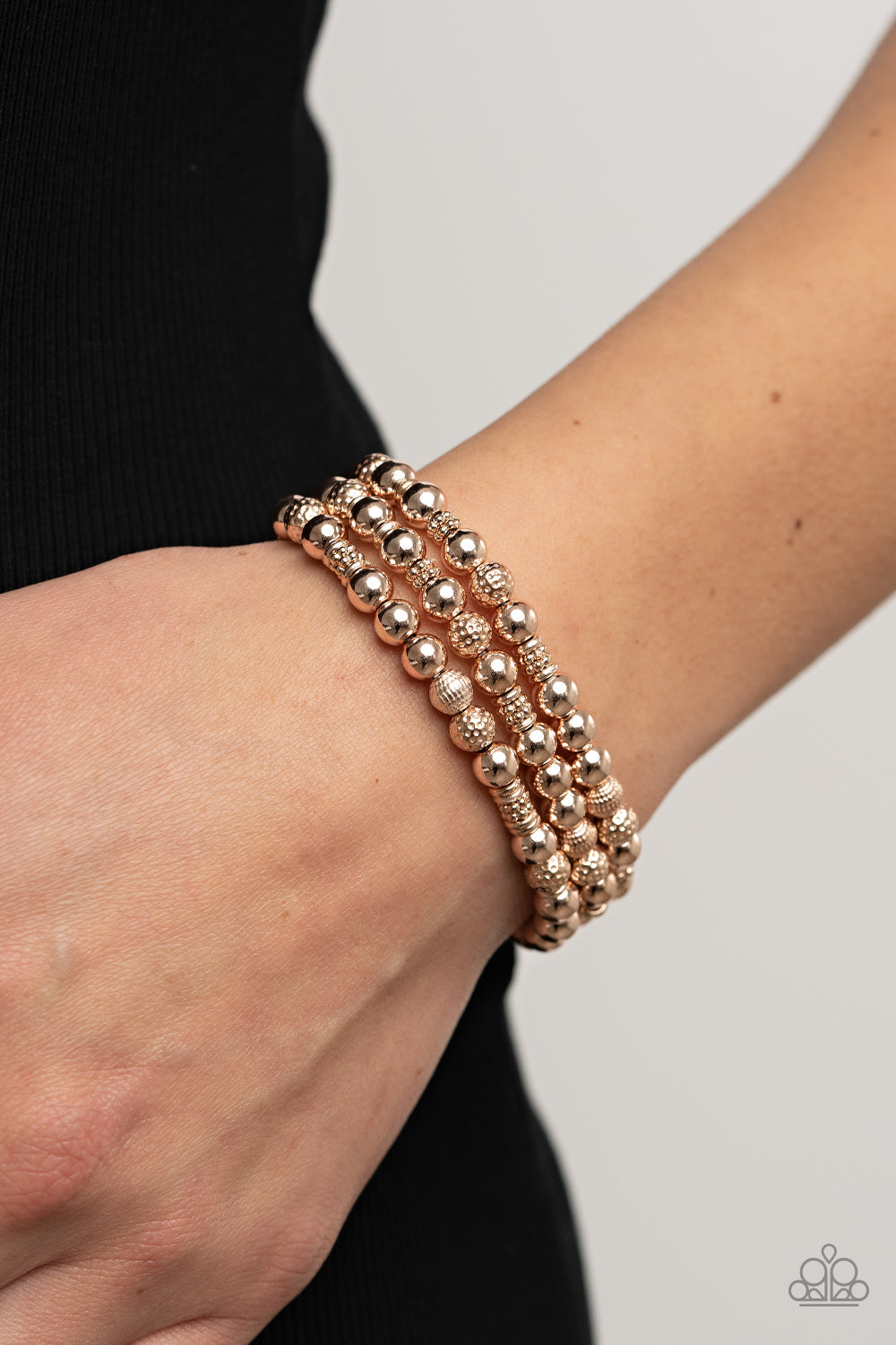 Paparazzi Accessories - Boundless Boundaries - Rose Gold Bracelets a shiny collection of smooth, studded, and textured rose gold beads are threaded along stretchy bands around the wrist, creating dainty layers. Sold as one set of three bracelets.