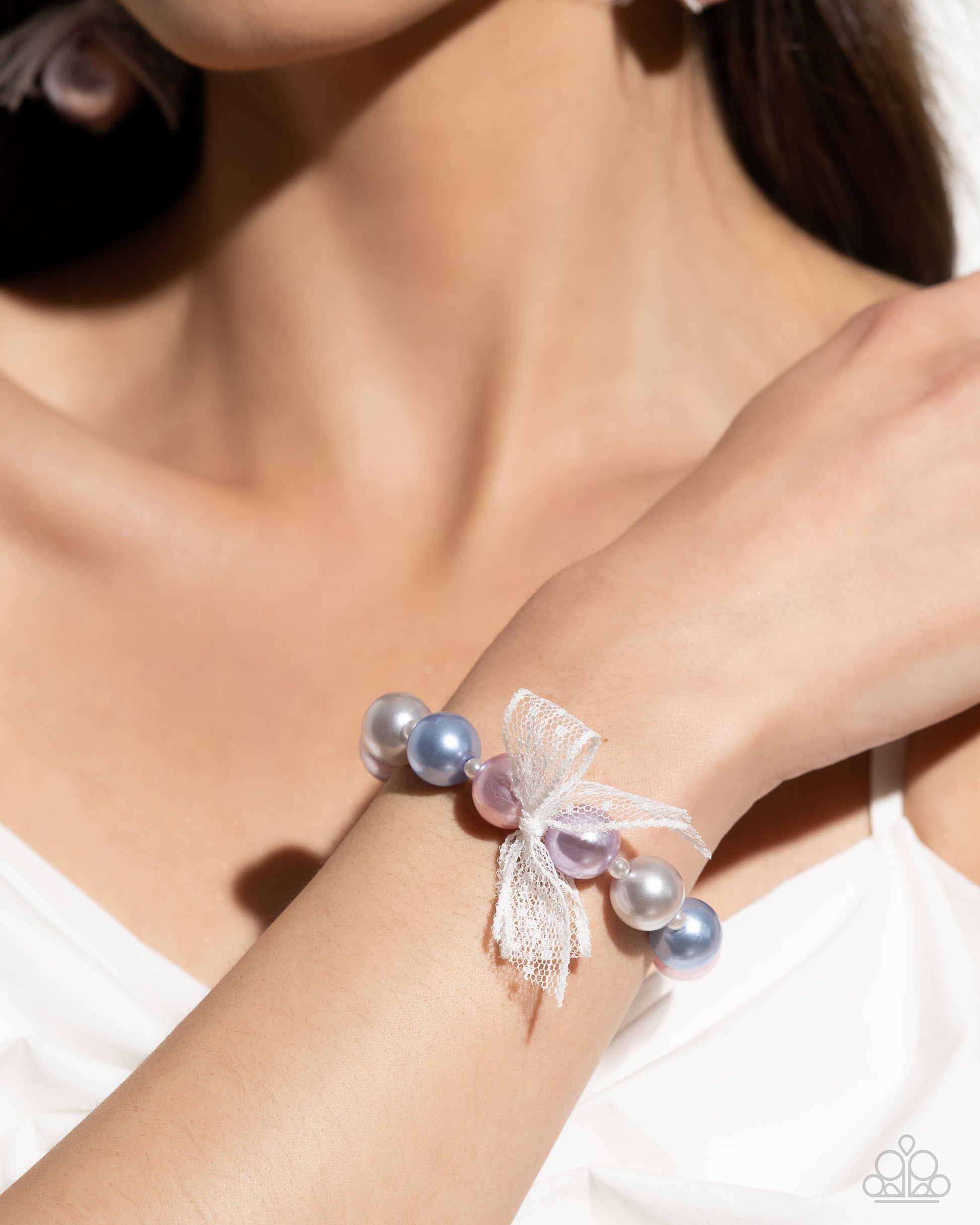 <p data-mce-fragment="1">Two glossy pearls one in blue and one in pink stack atop one another while an airy, chiffon white ribbon is tied in the center of the pearls for a refined finish. Earring attaches to a standard fishhook fitting.</p> <p data-mce-fragment="1"><i data-mce-fragment="1">Sold as one pair of earrings.</i></p>