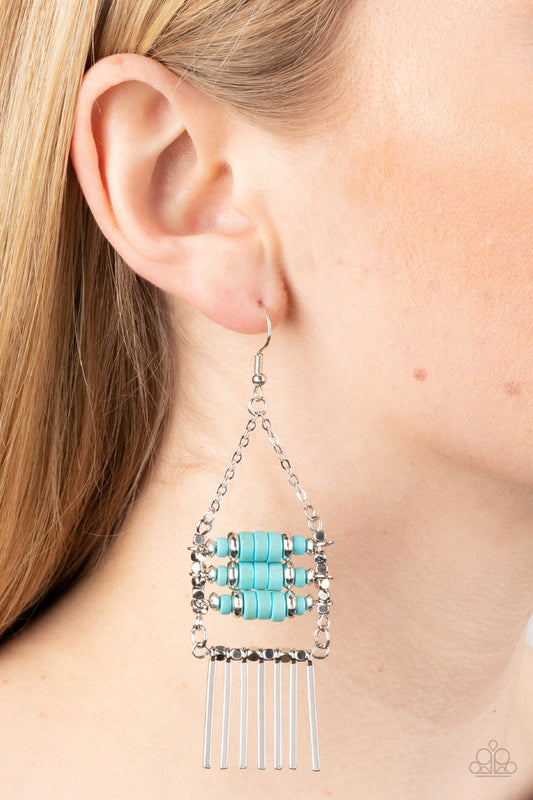 Rows of cylindrical silver and turquoise stone beads are threaded along metal rods between faceted silver cubes. Silver rods stream out from the bottom of the stacked display, resulting in an earthy fringe. Earring attaches to a standard fishhook fitting.  Sold as one pair of earrings.