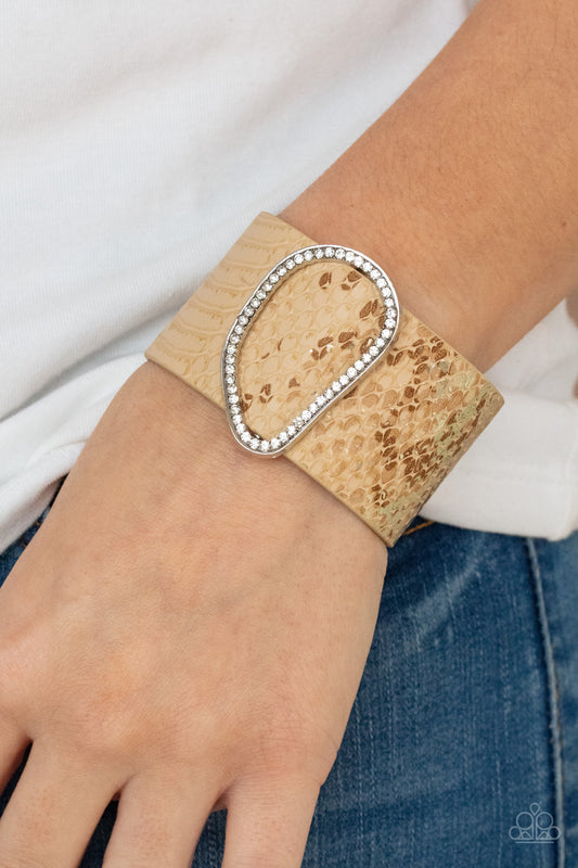 HISS-TORY In the Making - Brown Wrap Bracelets  En&ncrusted with glassy white rhinestones, an asymmetrical silver fitting glides along a tan leather band adorned in a golden metallic python print for a wild look. Features an adjustable snap closure.  Sold as one individual bracelet.  Paparazzi Jewelry is lead and nickel free so it's perfect for sensitive skin too!