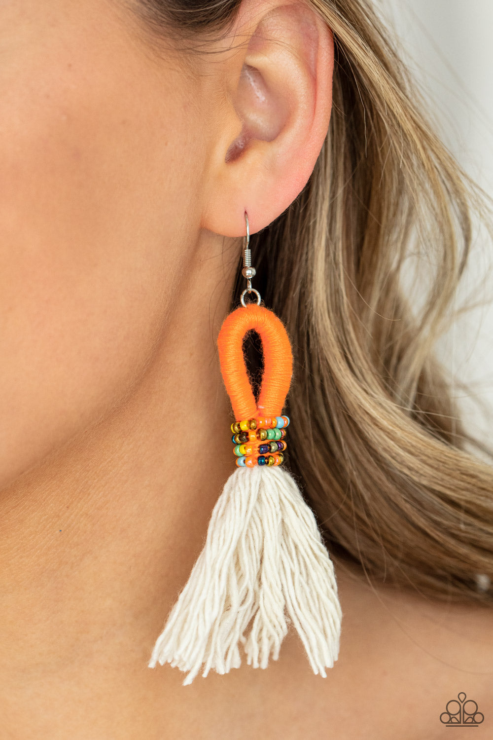 The Dustup - Orange Earrings a tassel of soft white cotton fans out under rows of brightly colored seed beads. Anchored by a loop of vibrant orange floss, the eye-catching style swings from the ear for a show-stopping statement. Earring attaches to a standard fishhook fitting. Sold as one pair of earrings. Paparazzi Jewelry is lead and nickel free so it's perfect for sensitive skin too!