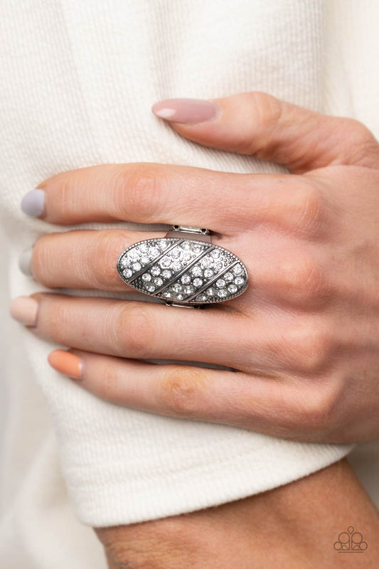 Galactic Glitz - White Ring rows of glassy white rhinestones slant across a stretched oval frame dotted in silver studs, creating a dramatic centerpiece atop the finger. Features a stretchy band for a flexible fit.  Sold as one individual ring.  Paparazzi Jewelry is lead and nickel free so it's perfect for sensitive skin too!