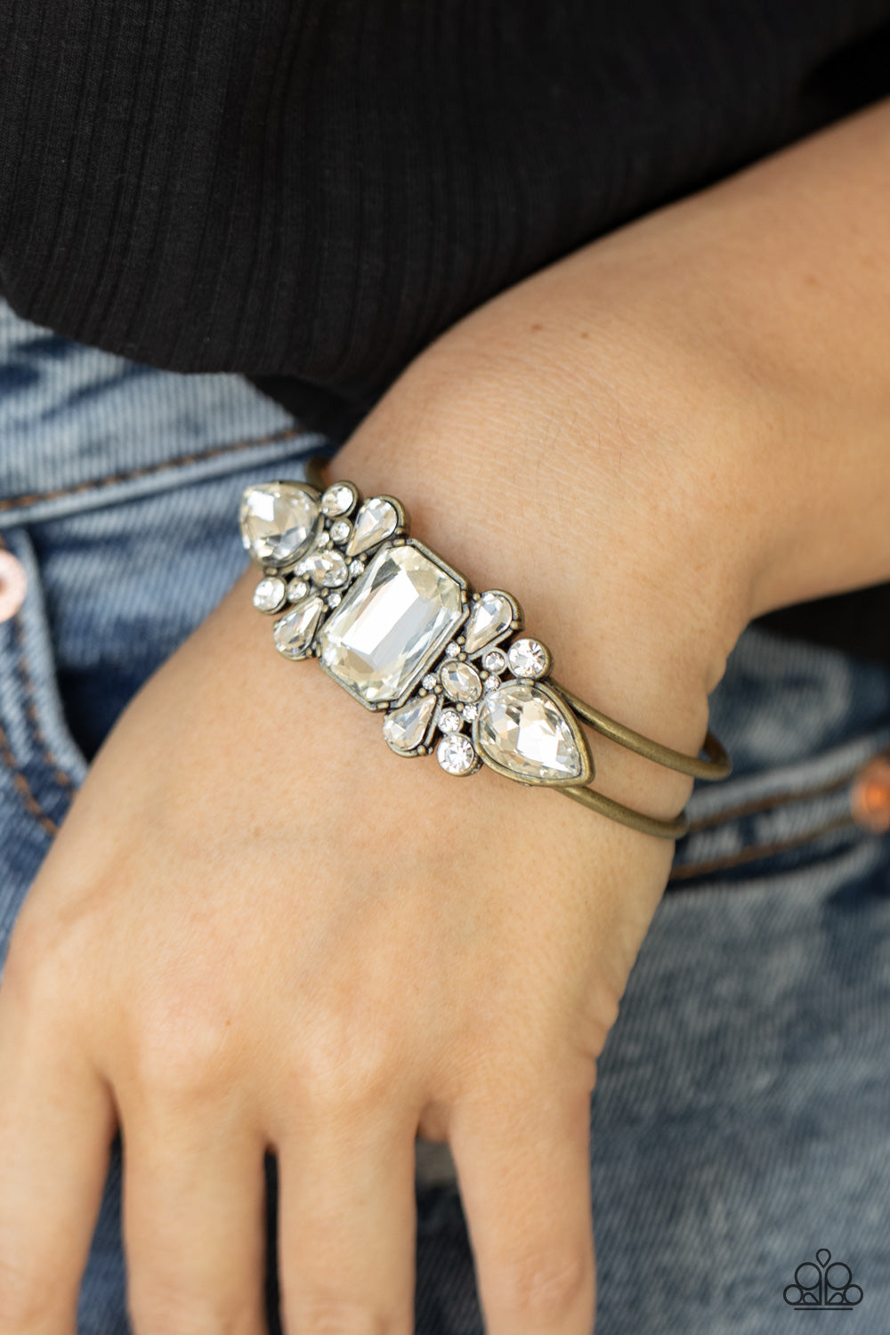 Call Me Old-Fashioned - Brass Hinge Rhinestone Bracelet featuring regal teardrop, oval, emerald, and round cuts, an explosion of oversized rhinestones neatly coalesce into a sparkly centerpiece atop an antiqued brass cuff for a dramatically dazzling display. Features a hinged closure. Sold as one individual bracelet. Paparazzi Jewelry is lead and nickel free so it's perfect for sensitive skin too!