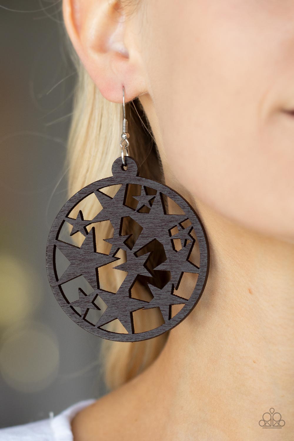 Cosmic Paradise - Brown Wood Star Earrings an oversized round brown wooden frame is filled with a cosmos of cut-out brown stars creating a whimsical statement. Earring attaches to a standard fishhook fitting.  Sold as one pair of earrings.