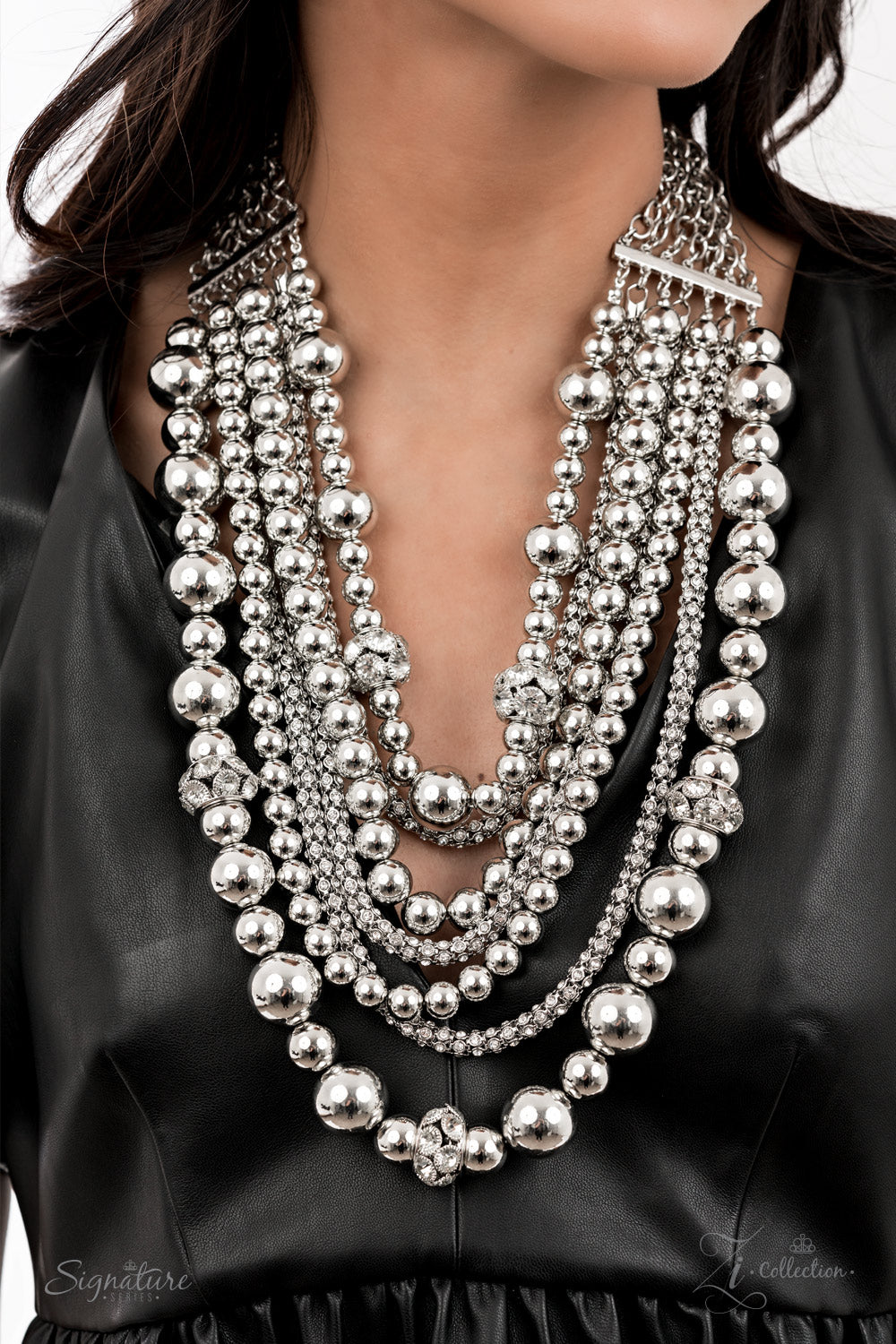 The Liberty - 2021 Zi Collection Necklace held together by rectangular silver frames, a couture-clutching collection of oversized silver beads interspersed with white rhinestone encrusted ornaments alternates with interlocking rows of white rhinestone encrusted chains across the chest. Edgily enhanced with linked rows of silver chain fittings, the emboldened silver layers demand to be seen with their unapologetic attitude. Features an adjustable clasp closure.