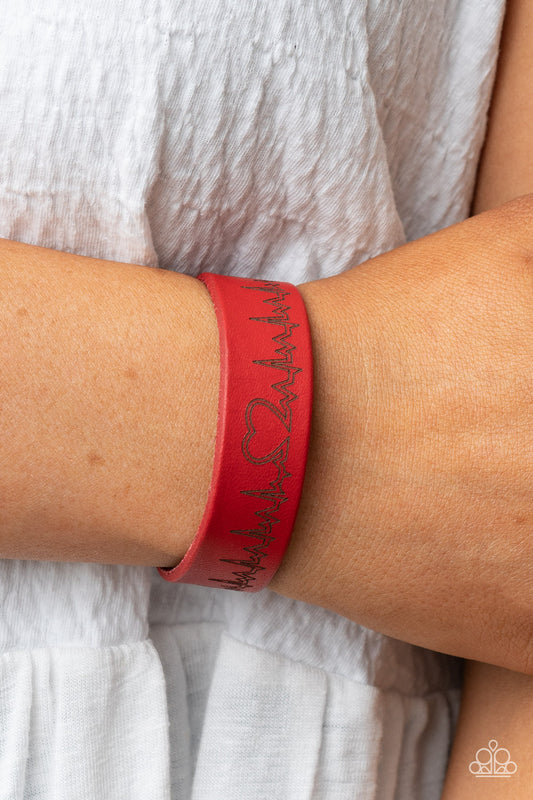 Haute Heartbeat - Red Heartbeat Wrap Bracelets culminating into a heart at the center, a zigzagging pattern reminiscent of a heartbeat is etched across the front of a red leather band around the wrist for a whimsical fashion. Features an adjustable snap closure.  Sold as one individual bracelet.