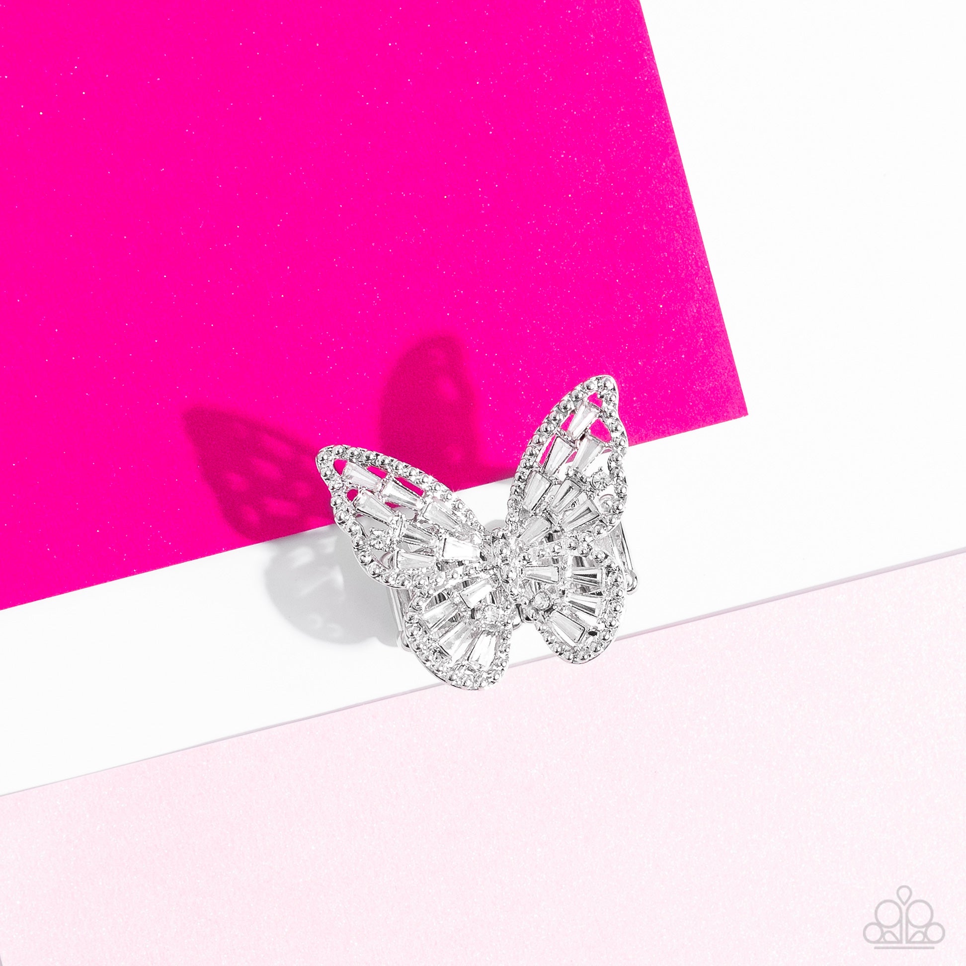 Paparazzi Accessories - Bright-Eyed Butterfly - White Rings a glitzy collection of emerald cut rhinestones are sprinkled across the studded wings of a shiny silver butterfly, resulting in a whimsical centerpiece atop the finger. Features a stretchy band for a flexible fit.  Sold as one individual ring.