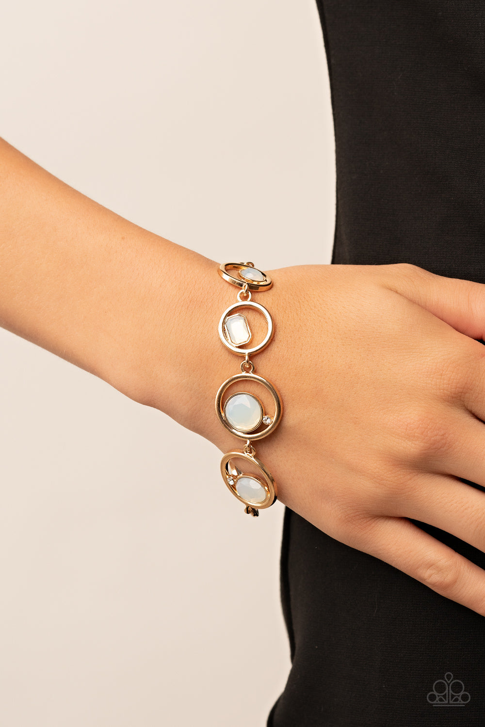 Paparazzi Date Night Drama - Gold Bracelets a sporadically infused with dainty white rhinestones, a glittery collection of round, teardrop, and emerald cut opal rhinestones haphazardly adorn the centers of interlocking gold hoops around the wrist for a mesmerizing finish. Features an adjustable clasp closure. Sold as one individual bracelet. Get The Complete Look! Necklace: "Big Night Out - Gold" (Sold Separately)