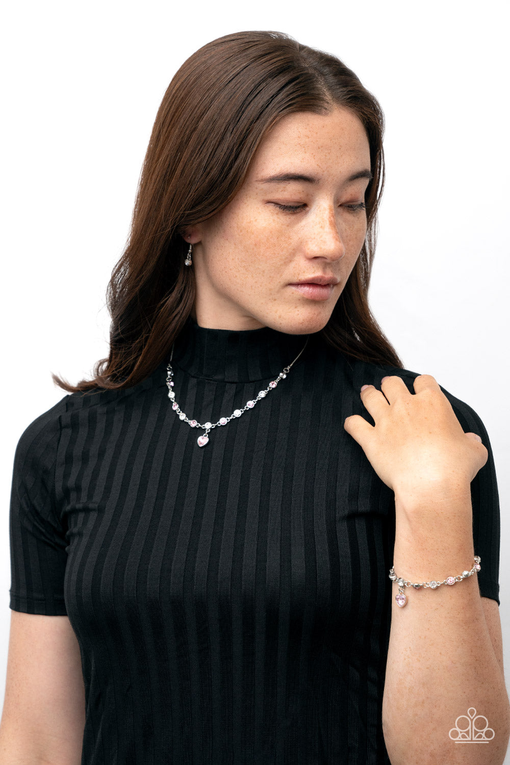True Love Trinket - Pink Heart Necklaces a pink rhinestone heart charm dances from a strand of white and pink rhinestones, resulting in a flirtatious sparkle below the collar. Features an adjustable clasp closure. Sold as one individual necklace. Includes one pair of matching earrings.