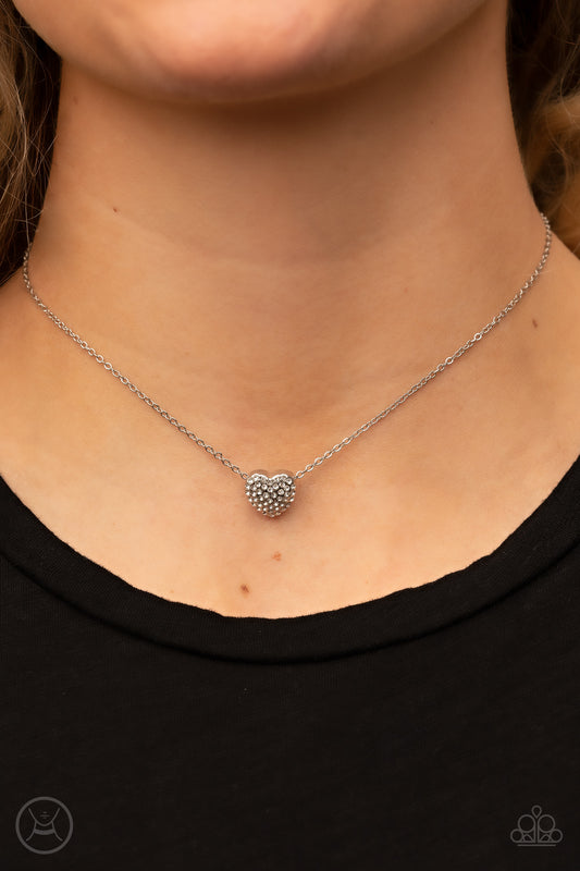 Twitterpated Twinkle - White Heart Rhinestone Choker Necklaces encrusted in glassy white rhinestones, a dainty heart frame sparkles along a dainty silver chain around the neck for a flirty finesse. Features an adjustable clasp closure.  Sold as one individual choker necklace. Includes one pair of matching earrings.