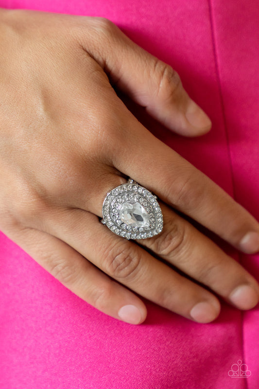 Icy Indulgence - White Rhinestone May Life of the Party Rings a dramatically oversized white teardrop gem twinkles inside two borders of glassy white rhinestones, resulting in a sparkly statement atop the finger. Features a stretchy band for a flexible fit.  Sold as one individual ring.