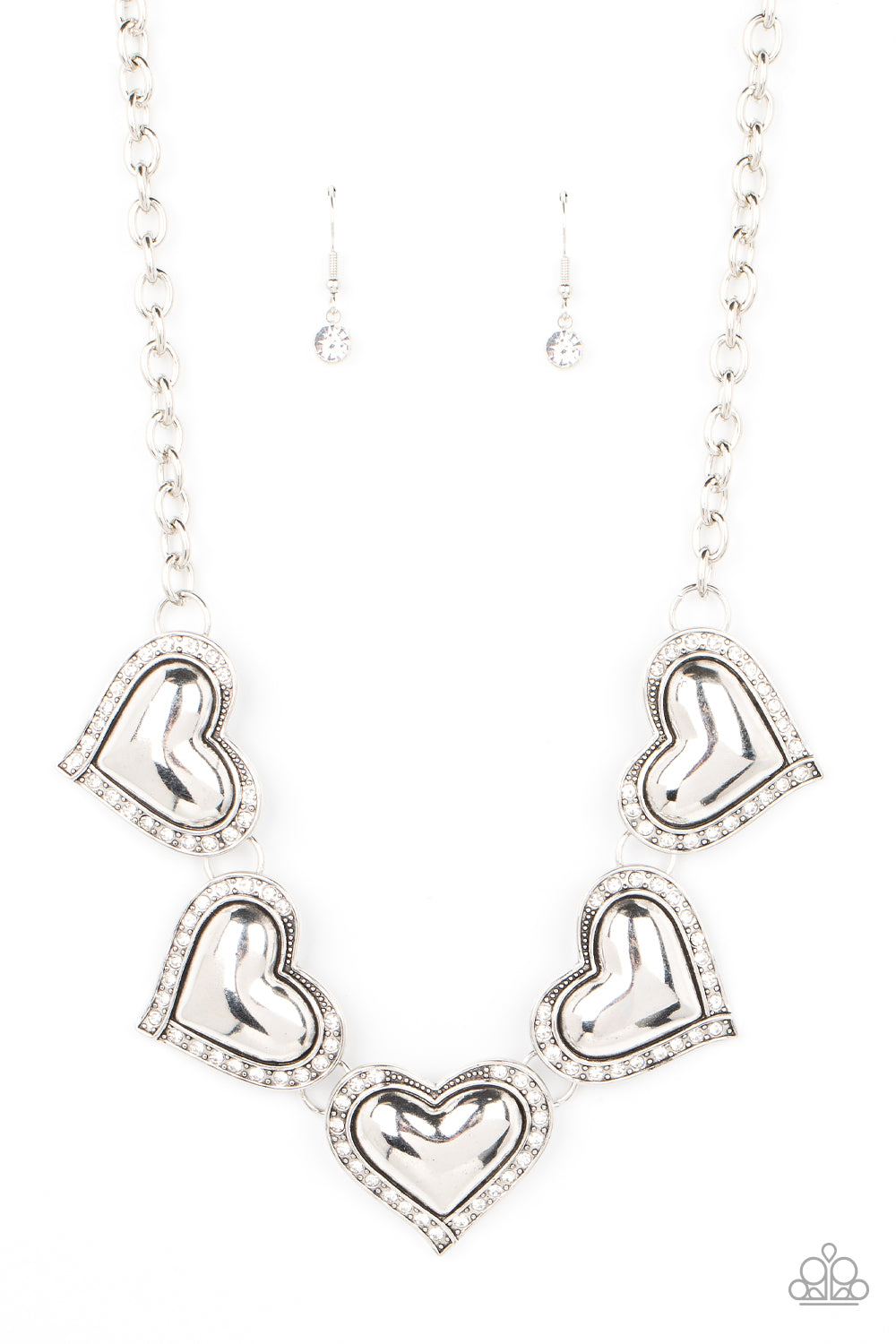 Paparazzi Kindred Hearts - White Heart Necklaces bordered in glassy white rhinestones, an oversized collection of beveled silver heart frames delicately links below the collar for a dramatically romantic look. Features an adjustable clasp closure.  Sold as one individual necklace. Includes one pair of matching earrings.