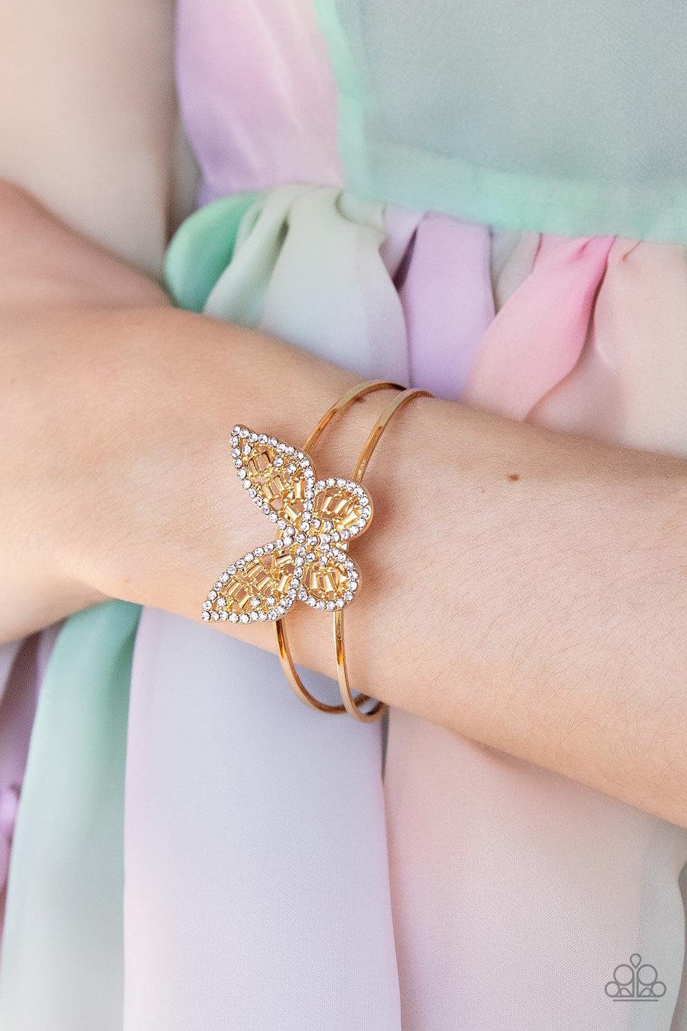 Paparazzi Butterfly Bella - Gold Butterfly Bracelets bordered in glassy white rhinestones, an airy gold butterfly is dotted in dainty white rhinestones and shiny gold emerald-like accents as it flutters atop a layered gold cuff for an enchanting fashion. Sold as one individual bracelet.