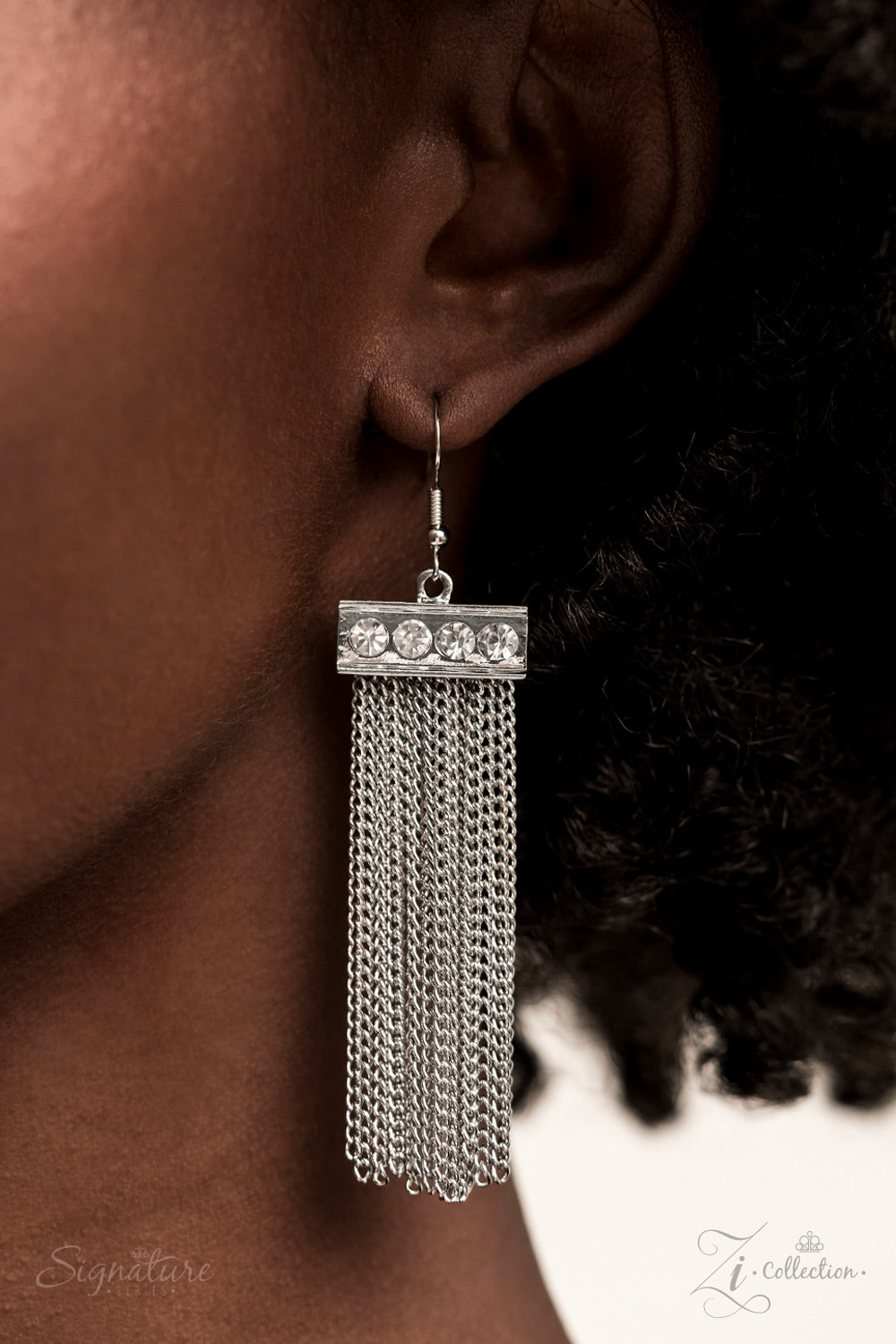 dramatically oversized, smoky, Asscher cut gem sits boldly at the bottom of a thick silver chain, creating a majestic focal point. An emerald cut gem in the same smoky hue connects to the bottom of the large centerpiece, followed by a thick silver bar lined with sparkling white rhinestones. The jaw-dropping frames stack into a mesmerizing pendant that gives way to a stream of silver chains, captivating onlookers with every swish of its spellbinding sashay.