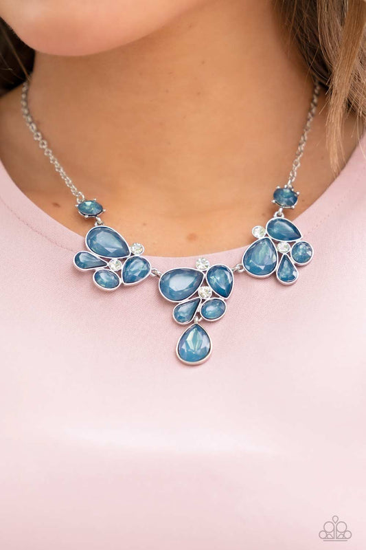 Paparazzi Accessories Everglade Escape - Blue Convention Necklaces draped elegantly across the chest, clusters of geometric blue gems, brushed in the fall Pantone® of Midnight, gather around sparkling white rhinestones, creating a bright and beautiful pattern. Features an adjustable clasp closure.  Sold as one individual necklace. Includes one pair of matching earrings.  2022 Glow Convention