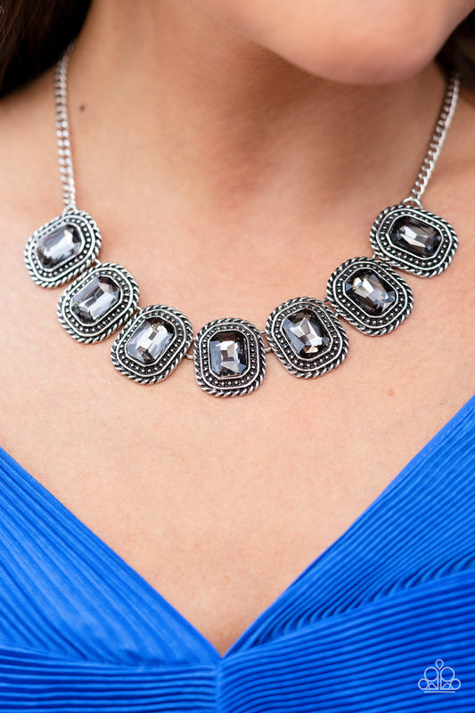 Paparazzi Accessories Iced Iron - Silver Convention Necklaces pressed into silver, chain-like frames, radiant-cut hematite rhinestones smolder below the collar in a jaw-dropping finish. Features an adjustable clasp closure.  Sold as one individual necklace. Includes one pair of matching earrings.  2022 Glow Convention