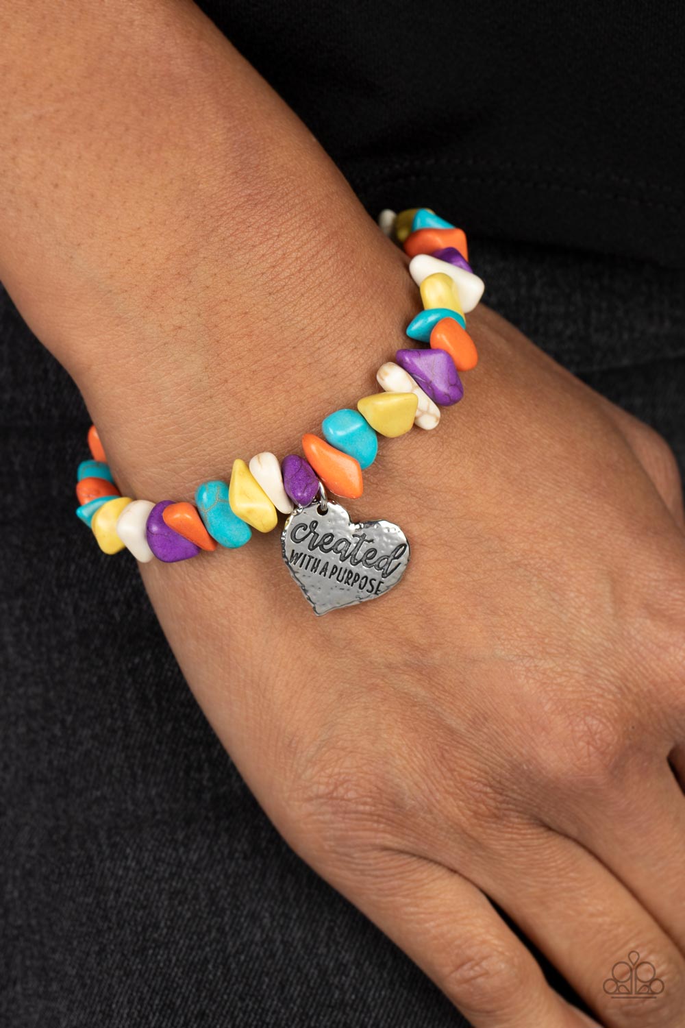 Bracelets an assortment of chiseled orange, turquoise, yellow, purple, and white stones are threaded along an elastic stretchy band in a free-spirited pattern. A silver heart charm, hammered in antiqued texture is engraved with the words "created with a purpose" for an inspiring finish. As the stone elements in this piece are natural, some color variation is normal. Sold as one individual bracelet.