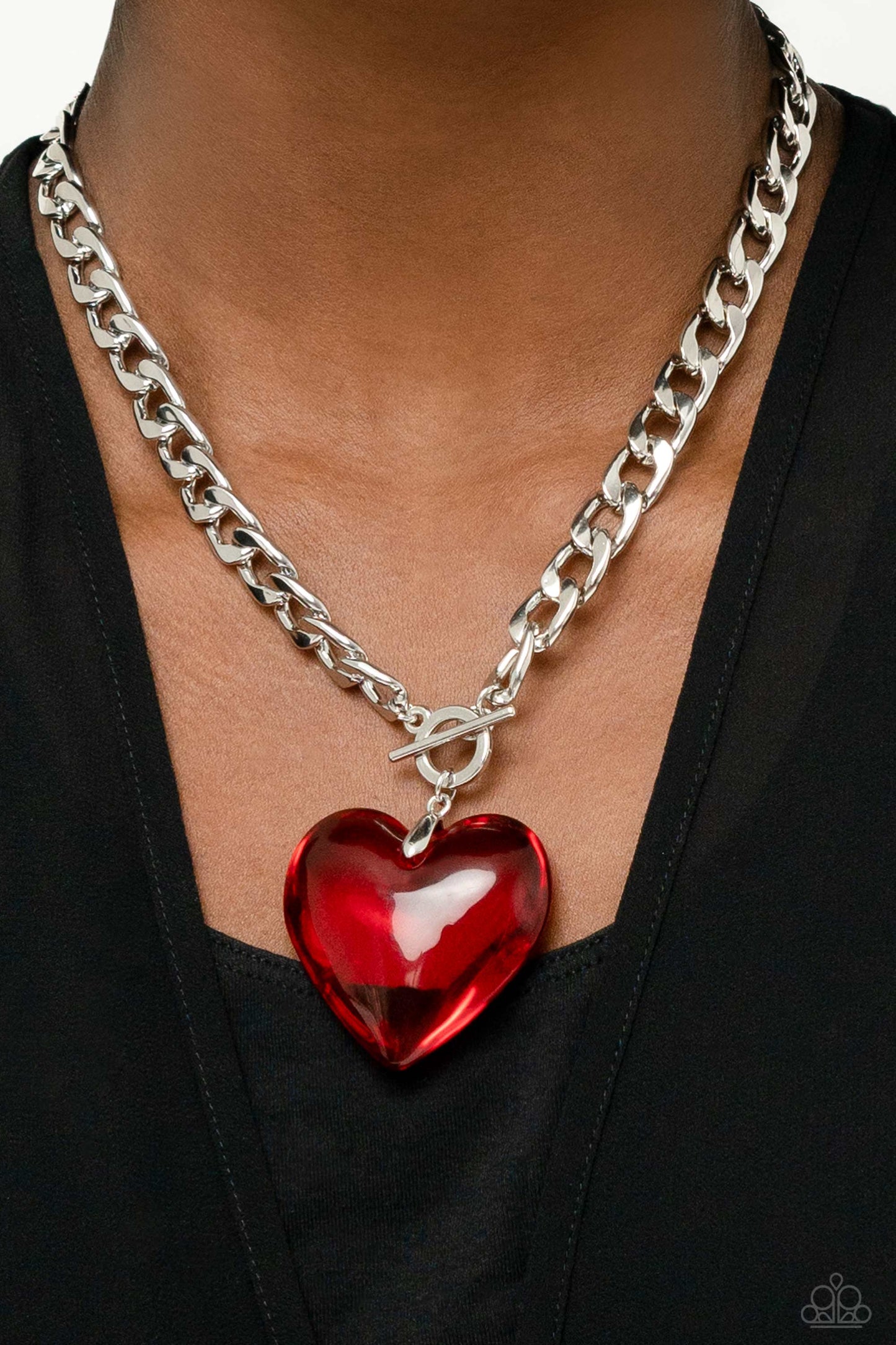 Featuring a glossy finish, an oversized, rich, red heart gem swings from the bottom of a thick silver curb chain below the collar for a romantic declaration. Features a toggle closure. Sold as one individual necklace. Includes one pair of matching earrings.
