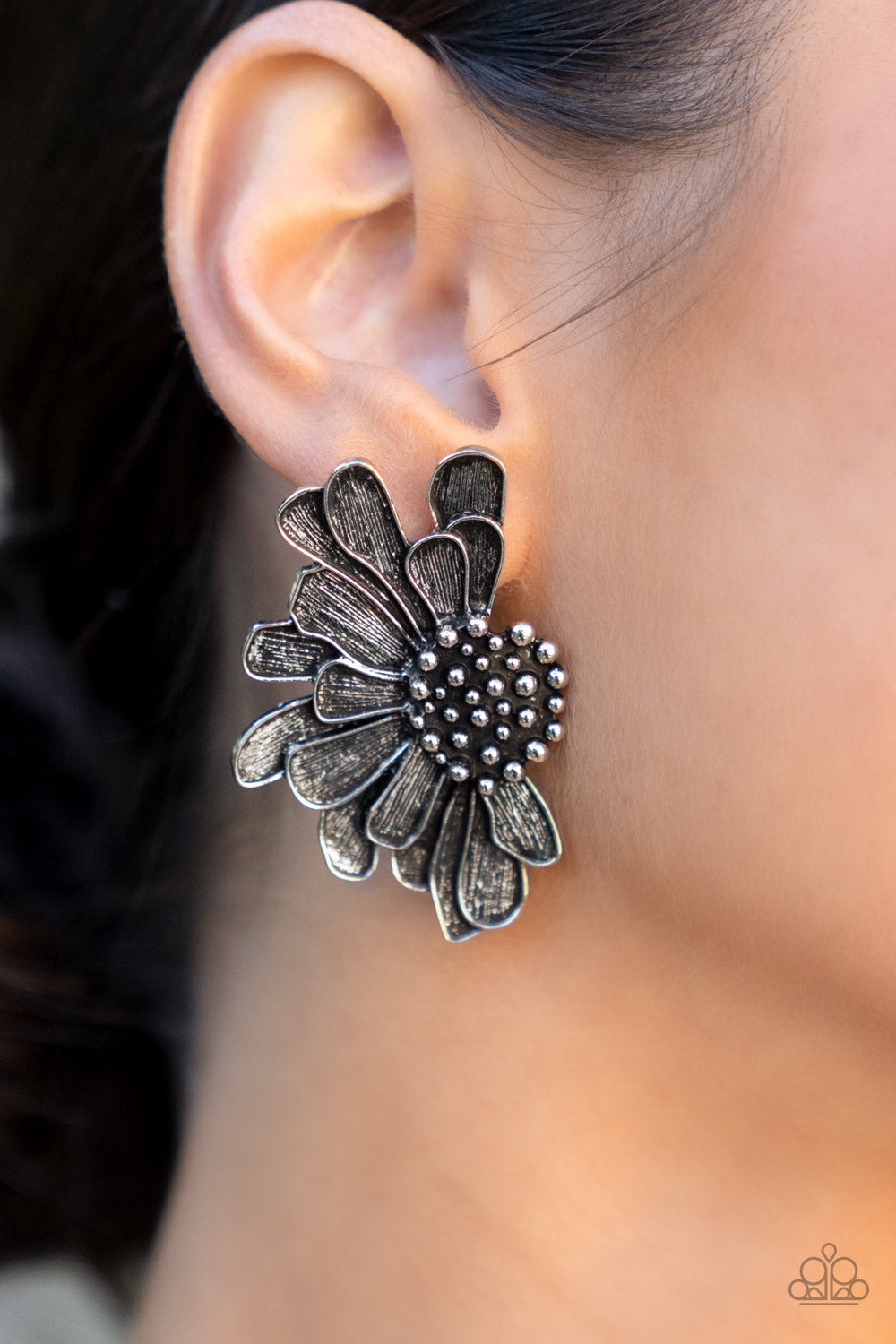 Paparazzi Farmstead Meadow - Silver April Life of the Party Earrings imperfect silver petals bloom from a studded center, layering into a rustic half blossom for a whimsical flair. Earring attaches to a standard post fitting.  Sold as one pair of post earrings.  Life of the Party exclusive item April 2022.