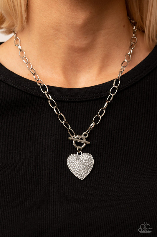 If You LUST - White Rhinestone Heart Necklaces a white rhinestone dotted silver heart frame sparkles from a toggle closure at the center of an oval silver linked chain for a flirtatious fashion. Features a toggle closure.  Sold as one individual necklace. Includes one pair of matching earrings.