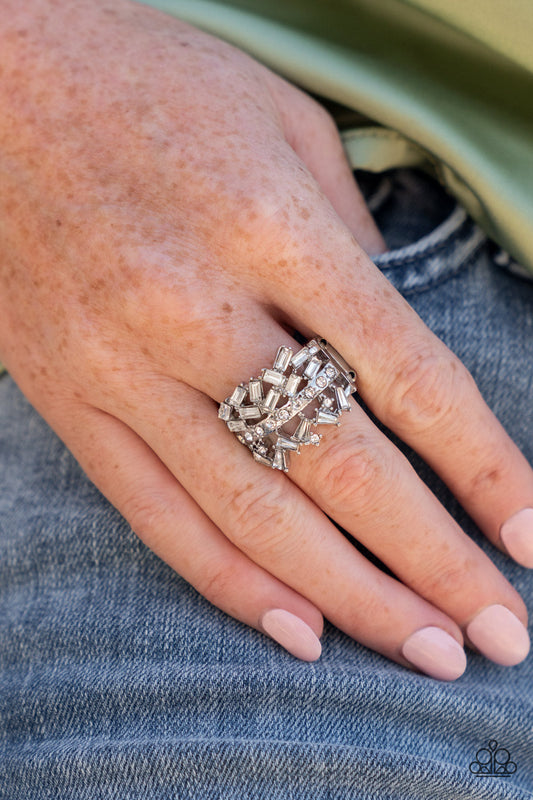 Paparazzi Scattered Sensation - White April 2022 Life of the Party Rings dotted in dainty white rhinestones, a single silver band separates a haphazard explosion of round and emerald cut rhinestones across the finger. Features a stretchy band for a flexible fit.  Sold as one individual ring.   Life of the Party exclusive item April 2022.