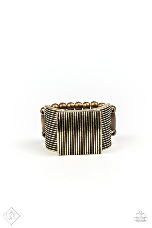 Etched in linear texture, a bold brass square sits atop a thick brass band radiating with alternating linear patterns, creating an edgy centerpiece. Features a stretchy band for a flexible fit.  Sold as one individual ring.